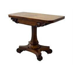 Early Victorian rosewood card table, rectangular foldover swivel top with rounded corners, red baize-lined surface, frieze adorned with carved foliate motifs, supported by a central octagonal waisted column on shaped quatrefoil base, terminating in scrolled feet with concealed metal castors