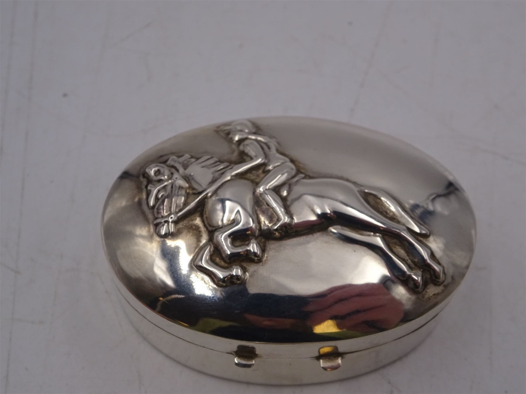 Four silver boxes, comprising oval example embossed with horse and rider, a rectangular example set with heart shaped amethyst, an oval example with set with carved abalone shell portrait, and a circular example set with Victorian penny, all hallmarked 