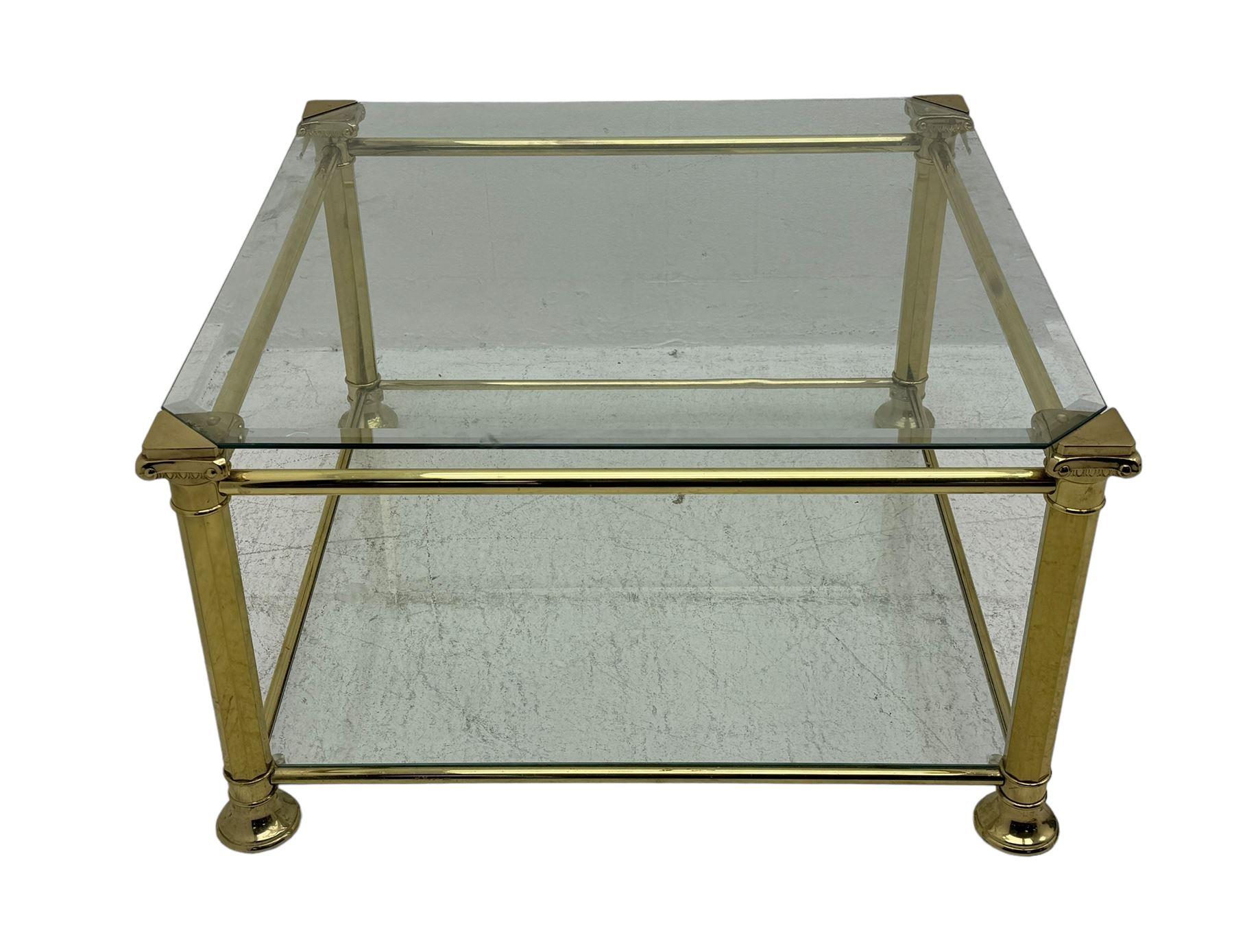 Mid 20th century brass and glass coffee table, square glass top with bevelled edges over undertier, supported by brass columns joined by crossbars, on circular feet