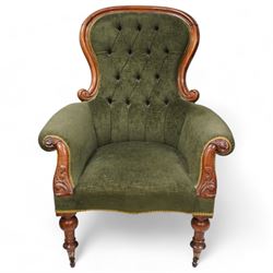 Victorian mahogany spoonback armchair, moulded frame with scroll carved terminals, upholstered in buttoned green fabric, rolled arms with foliage scroll carved facias, on turned front feet with brass cups and castors 