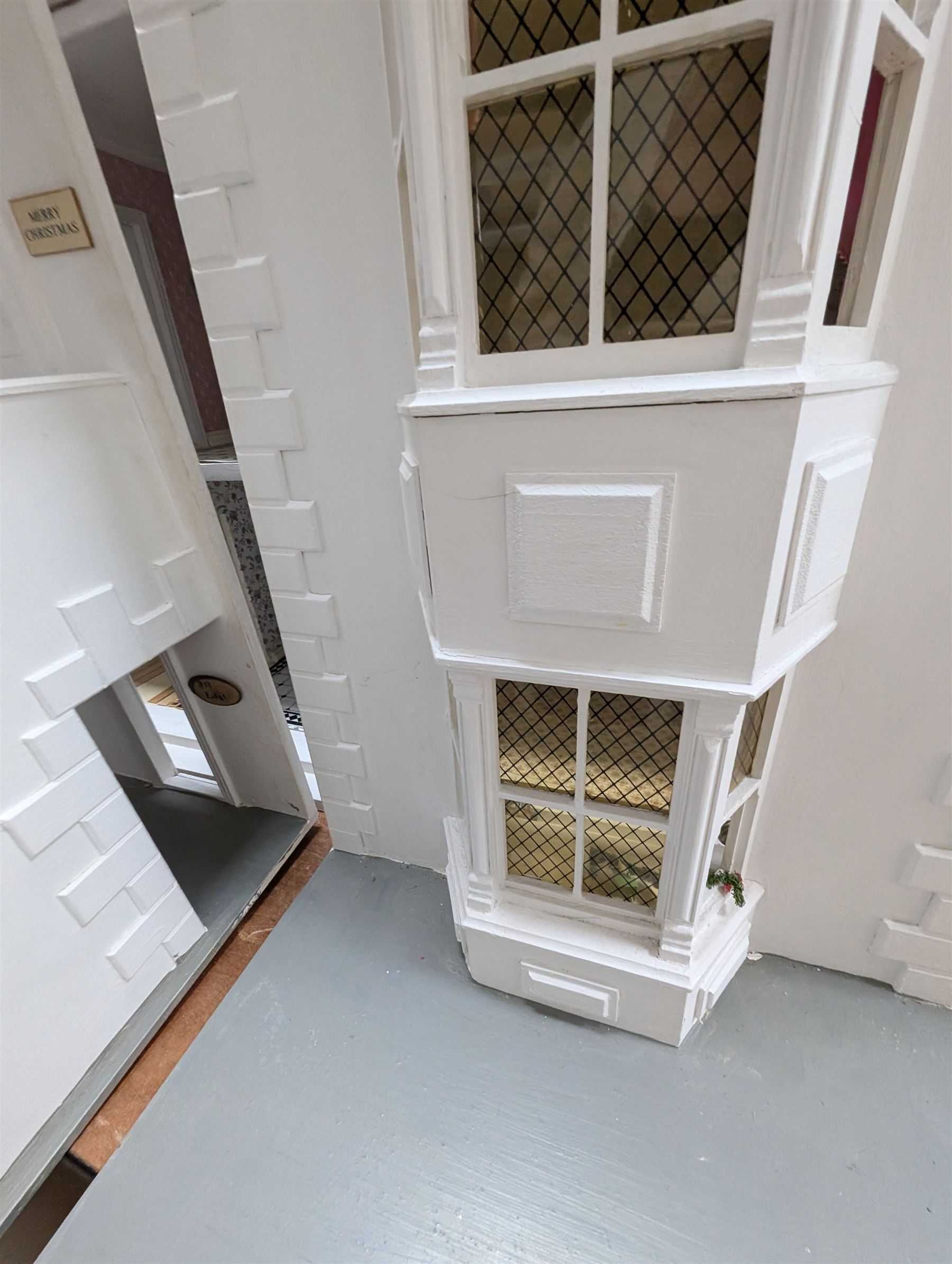 Large three storey modern dolls house, painted white with latticed windows, grey roof and metal fencing, with decorated interior, together with two dolls house garden rooms and two conservatories