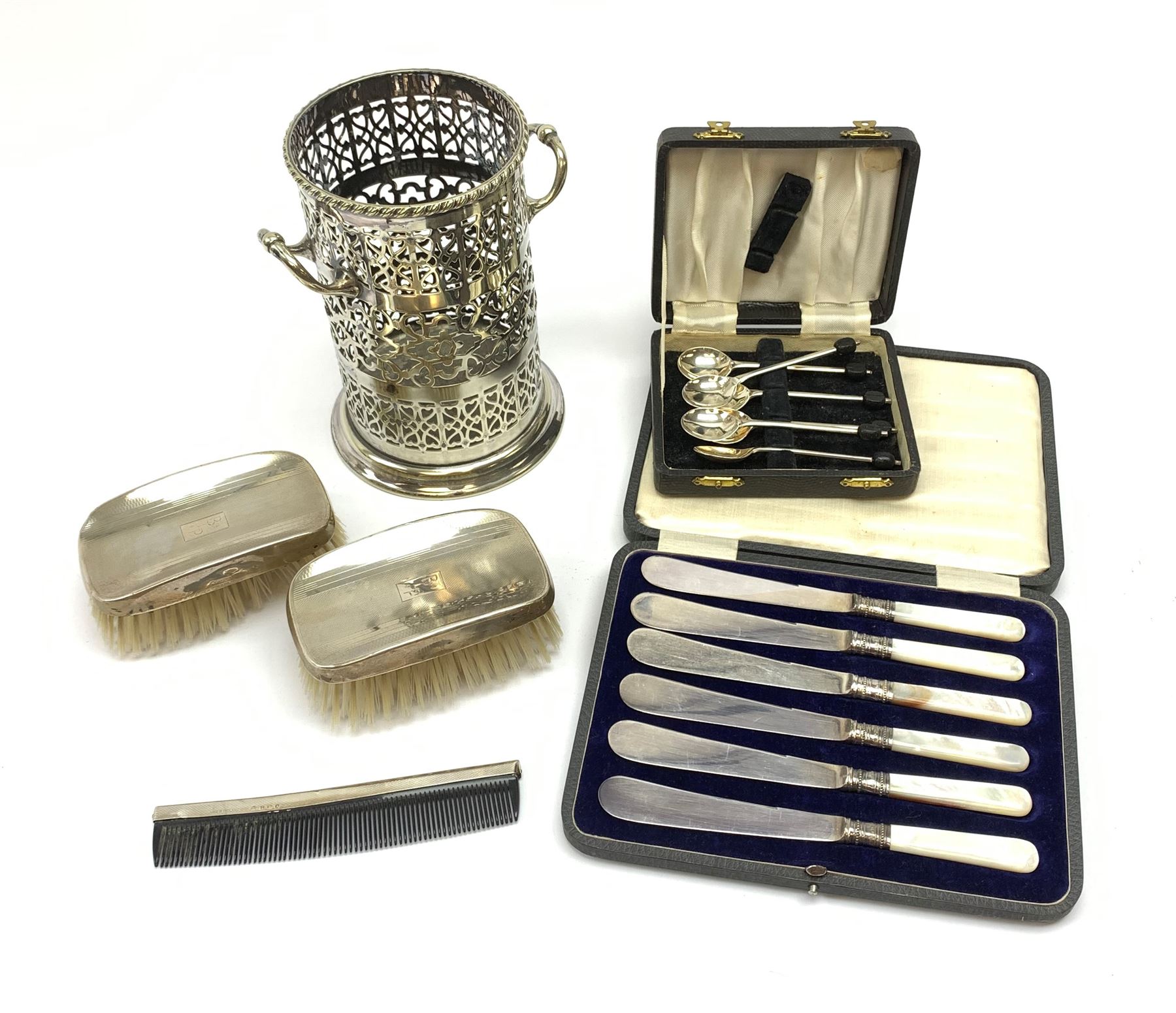 A pair of silver mounted clothes brushes, each with engine turned detail and monogramed central panel, and silver comb mount, all hallmarked Adie Brothers Ltd, Birmingham, date letters worn and indistinct, together with a cased set of six mother of pearl knives with silver ferrules, hallmarked William Yates Ltd, Sheffield 1916, a silver plated bottle coaster, with pierced sleeve and twin handles, marked beneath for Daniel and Arter, Birmingham, and a set of six silver plated coffee bean spoons. 