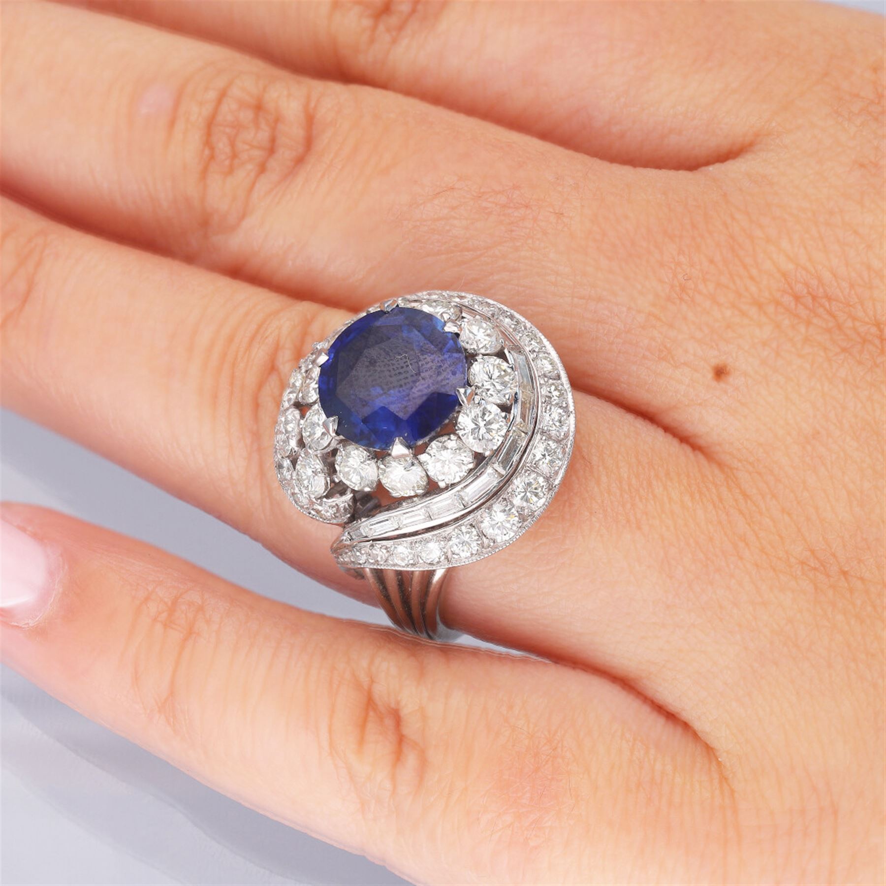 Platinum Ceylon sapphire and diamond, swirl design cluster ring, round cut sapphire of 4.56 carat, with CGL report, with baguette and round brilliant cut diamond surround, total diamond weight approx 4.30 carat