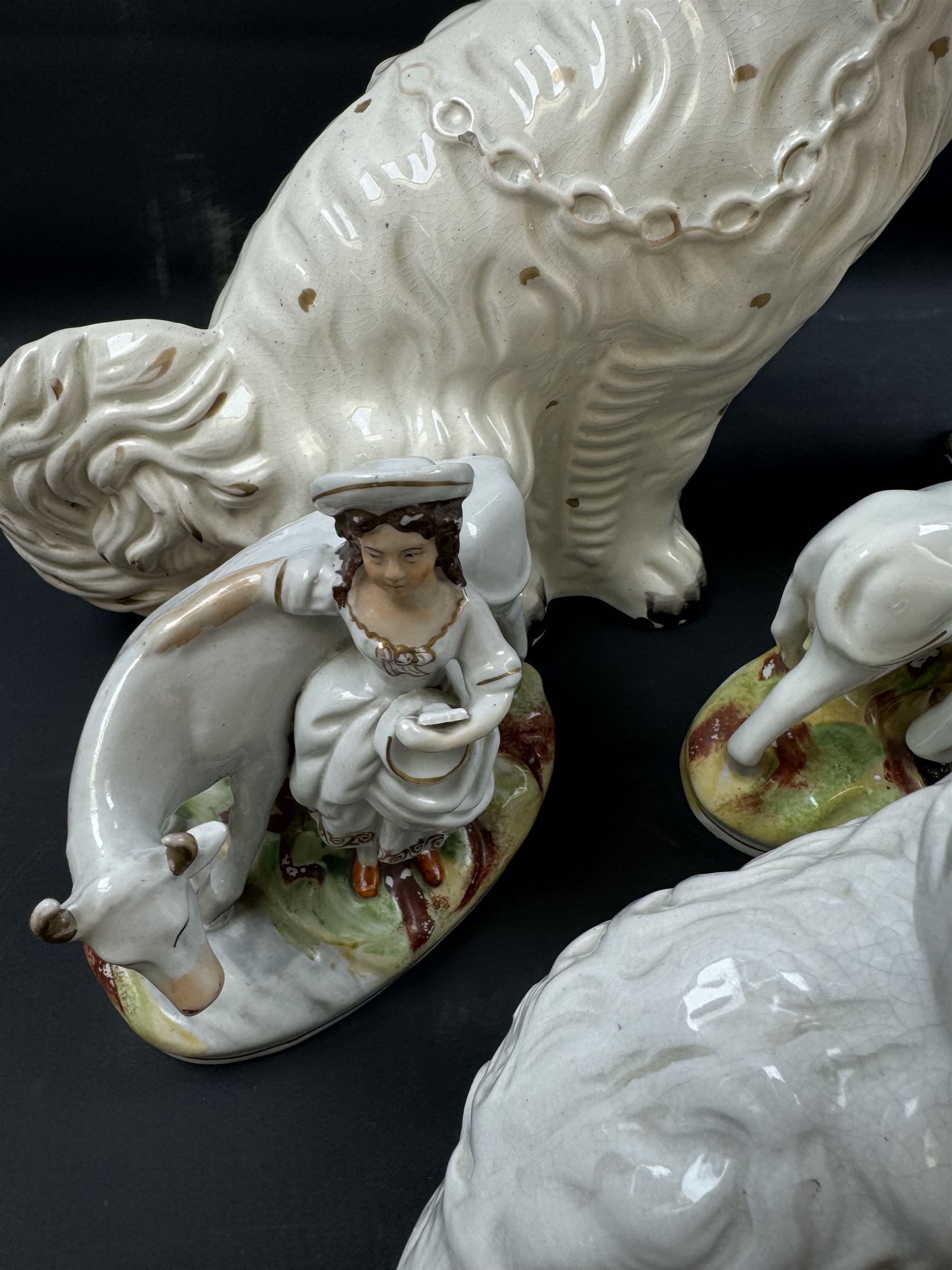 Staffordshire and Staffordshire style figures, to include a chained hound upon a blue oval base in the manner of Samuel Alcock, two pairs of seated Spaniels, a pair modelled as male figure and milk maid with cows, pair of recumbent Greyhounds, etc.