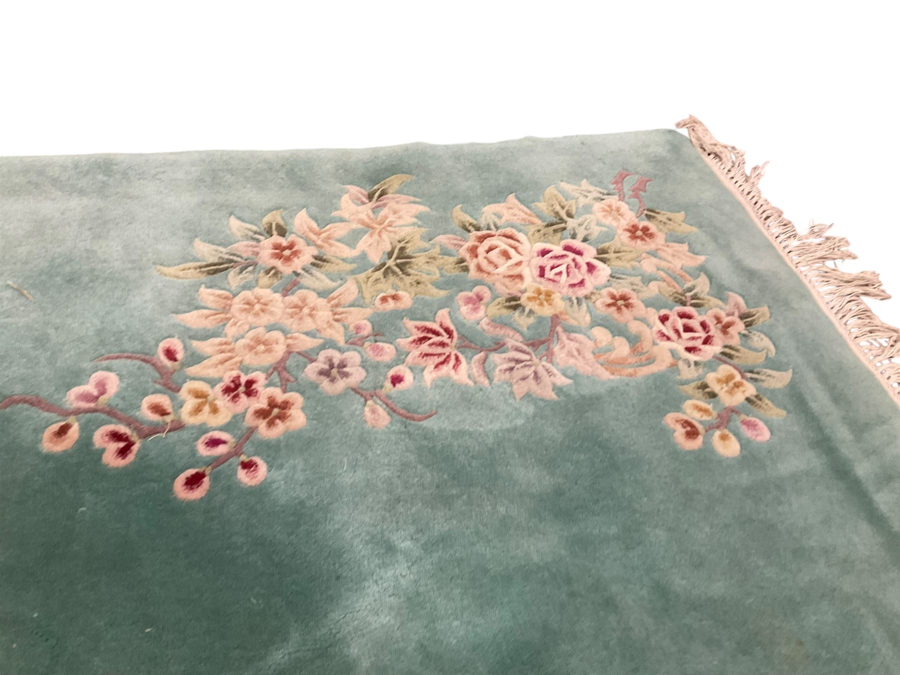 Chinese pale turquoise ground washed woolen rug, the plain field decorated with two large floral bouquet motifs with extending blossom and leafage