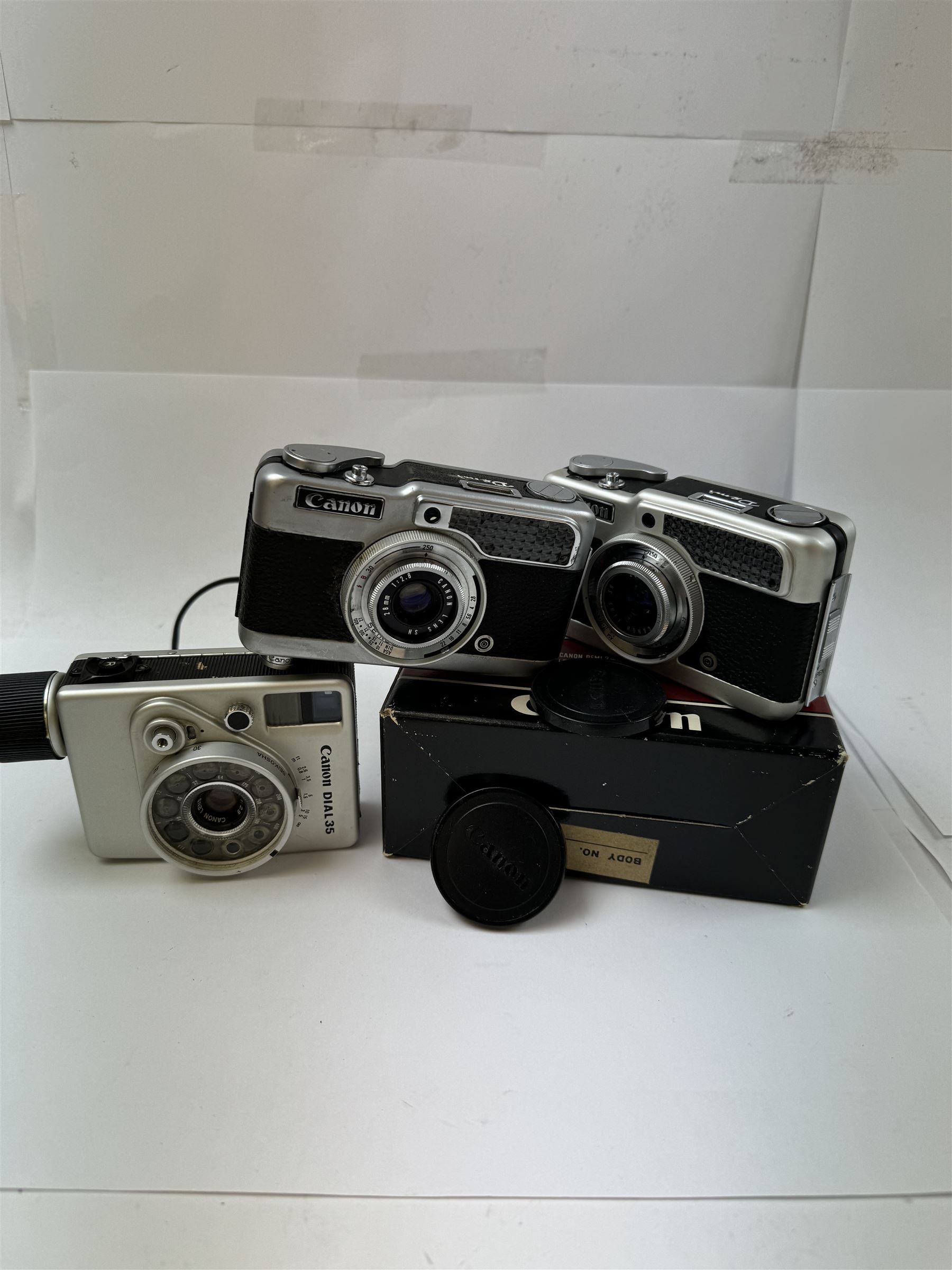 Three Canon half frame cameras, comprising two Canon Demi examples, serial nos. 243090 & 704714, one example boxed, and a Canon Dial35 serial no. 341572