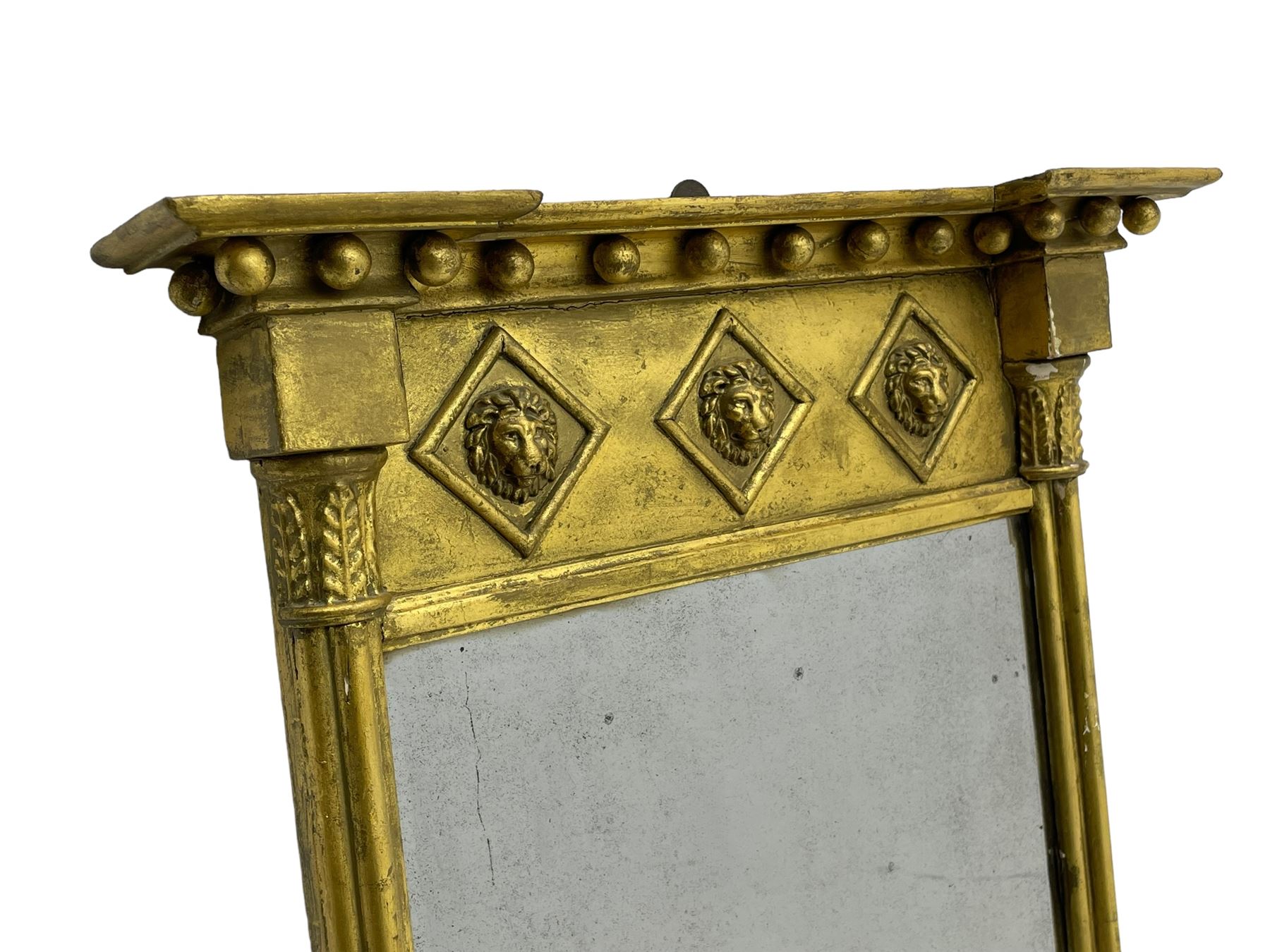 Regency giltwood and gesso pier mirror, projecting moulded cornice with globular mounts, the frieze decorated with three lion masks within lozenges, cluster column uprights with leaf decorated capitals, bevelled mirror plate