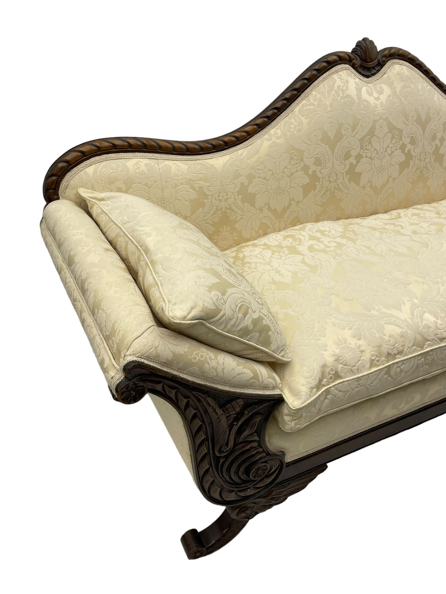 Victorian design walnut framed settee, shaped camelback with gadroon carved edge and central feather motif, upholstered in cream damask fabric with scrolling floral pattern, S-scroll arm facias carved with flower head and curled leaves, feather carved C-scroll splayed feet 