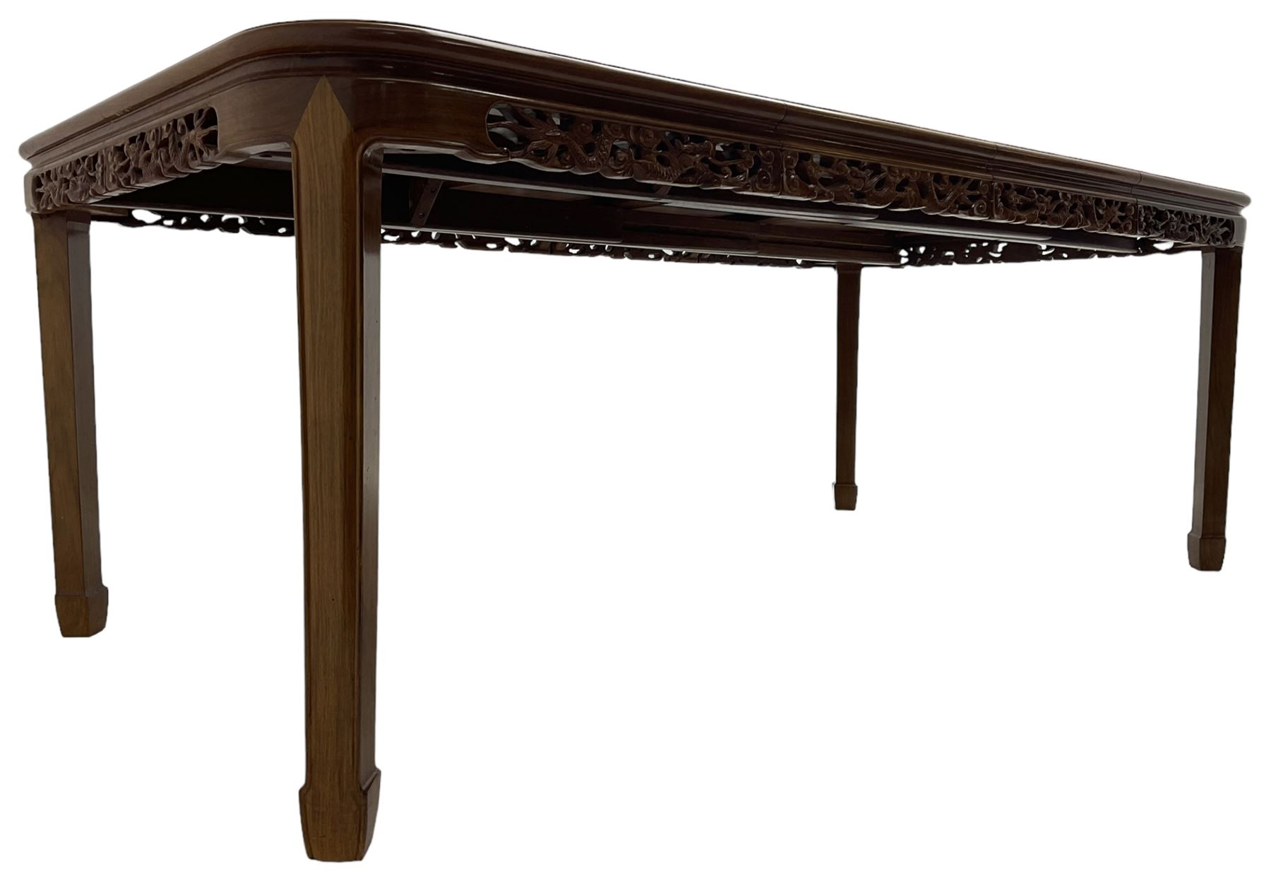 Late 20th century Chinese carved hardwood extending dining table, rectangular panelled top with rounded corners over a pierced frieze carved with dragon motifs and scrolling foliate decoration, with two additional leaves