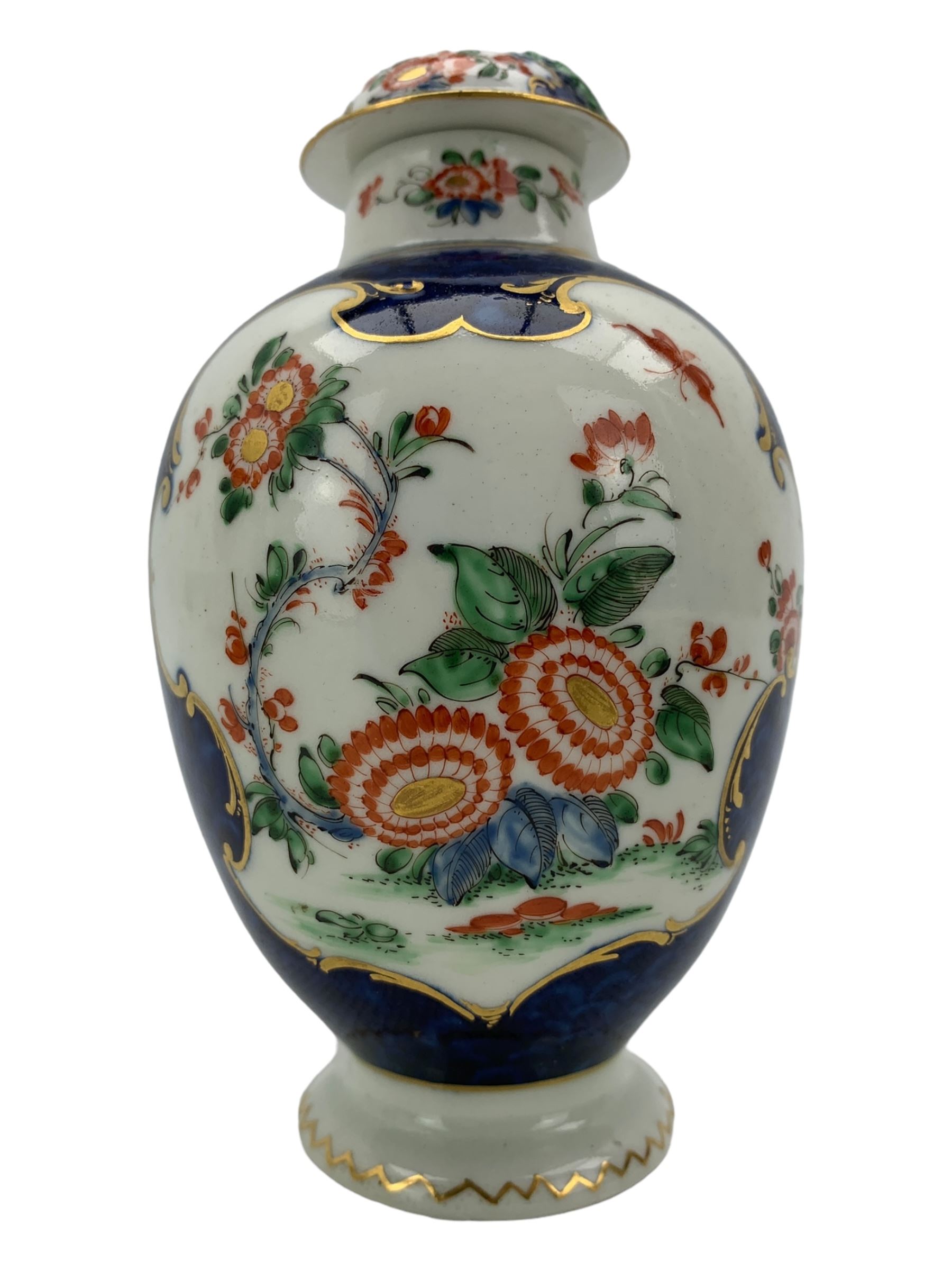 18th century Worcester tea caddy, of oval form and painted in the Kakiemon palette with reserves of flowers against a blue scale ground, H14cm together with a similar Worcester circular dish, painted with floral sprays, within a scalloped edge, blue crescent mark beneath, D19cm (2)