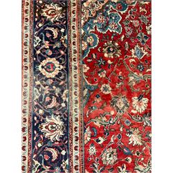 Persian Kashan crimson ground carpet, central shaped pale ground medallion surrounded by interlacing branches and stylised floral motifs, indigo main border with scrolling foliage design, within guard stripes 