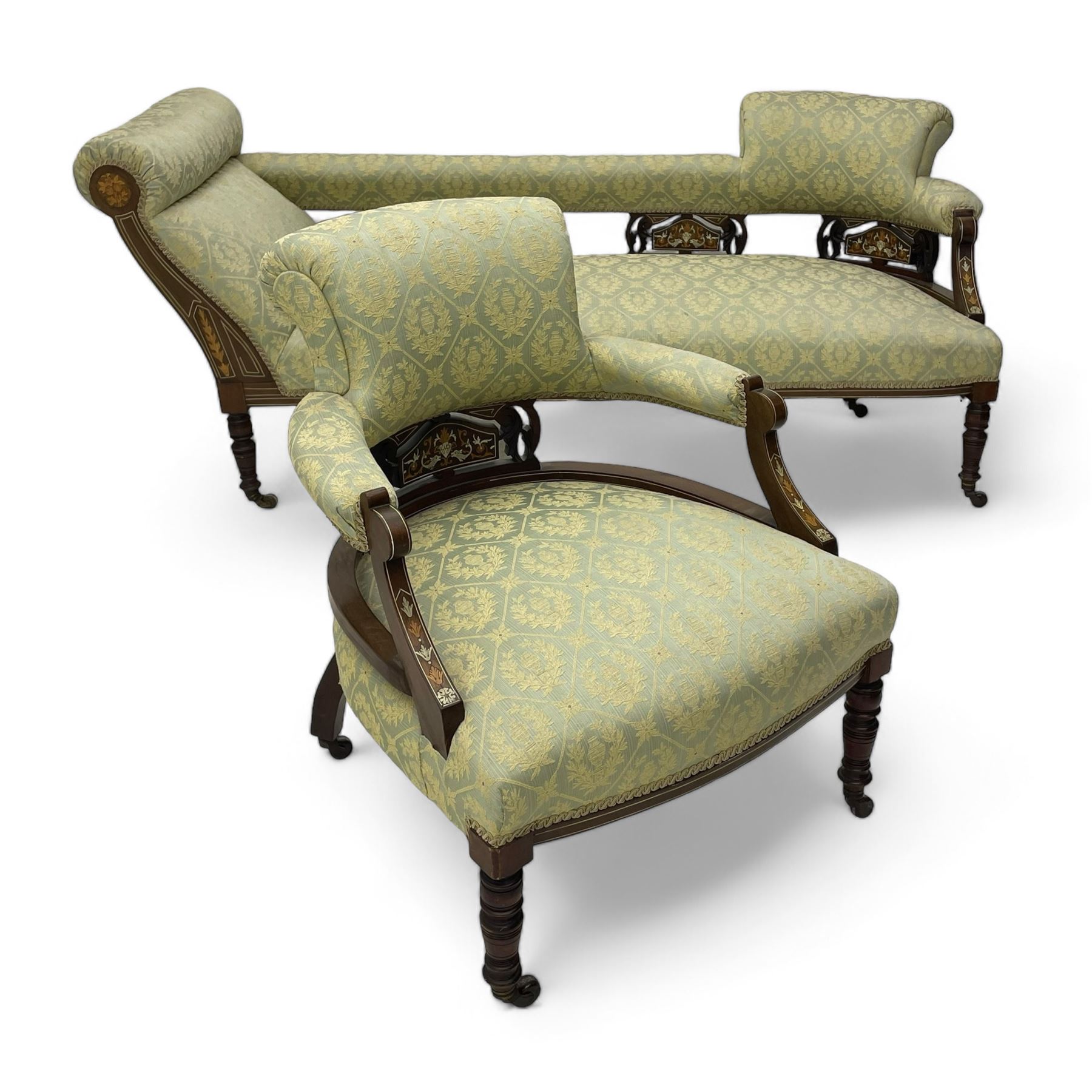 Late Victorian walnut salon settee or chaise lounge, double-ended with rolled back and curved end, upholstered in light aquamarine fabric with raised repeating lozenge pattern, decorated with laurel leaf wreaths and urns, three pierced splats carved with curled leaves, inlaid with dolphins and scrolled foliate motifs in simulated ivory and boxwood, on tapering ring turned supports with brass and ceramic castors (L166, D60, H70cm); together with matching tub-shaped armchair (W61cm, H73cm, D66cm)  