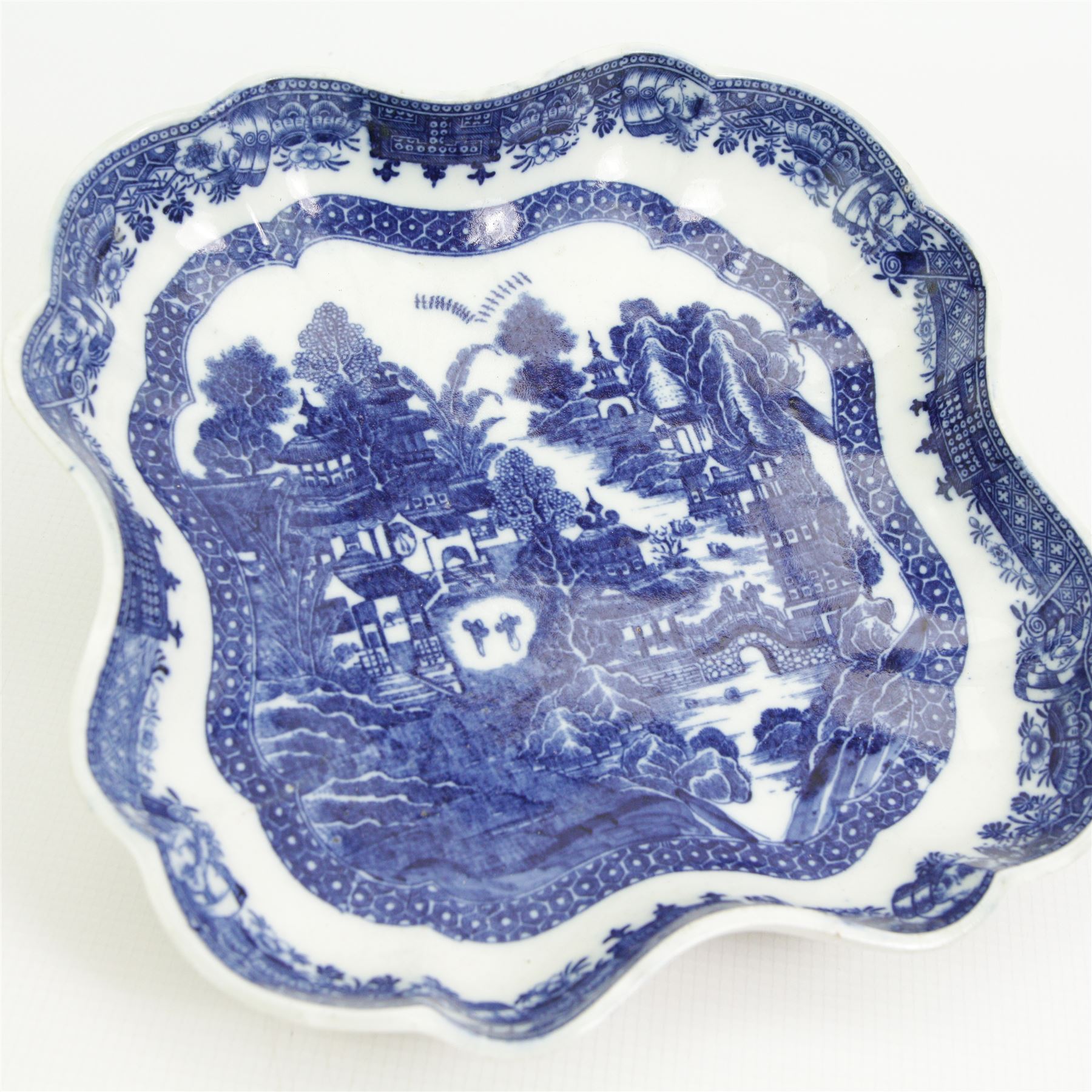 Caughley dessert dish, circa 1785-90, of lobed form and decorated in the Nankin pattern, W23cm together with a Worcester sauceboat, circa 1770-75, painted in underglaze blue with the Doughnut Tree pattern, L22cm 