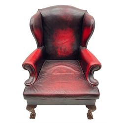 Georgian design hardwood-framed wingback armchair, upholstered in red leather, loose seat cushion and rolled arms, on acanthus carved ball and claw front feet 