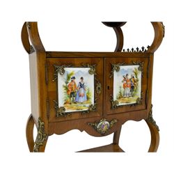 Mid-to-late 20th century French figured walnut three-tier bedside stand, shaped moulded top inlaid with figured book-matched veneers and crossbanding, double cupboard below enclosed by two doors mounted by painted porcelain panels depicting courting scenes within landscapes, on cabriole supports united by undertier, decorated with ornate cast metal cartouche mounts 