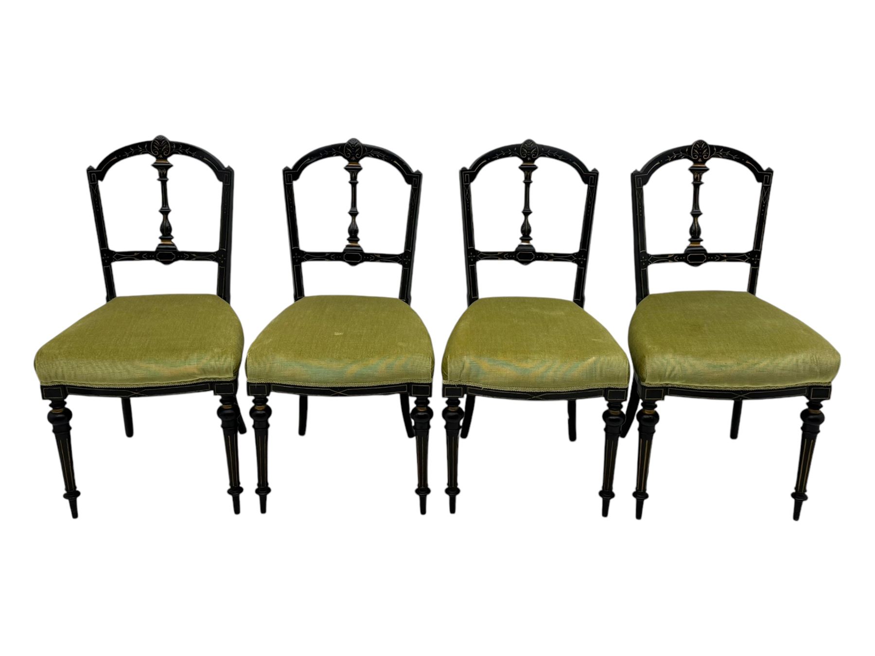 Set of four late Victorian ebonised dining chairs, decorated with carved and gilt foliate decoration, upholstered seats, on turned and fluted front supports 