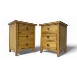 Pair of contemporary light oak bedside cabinets, projecting square tops over three drawers...