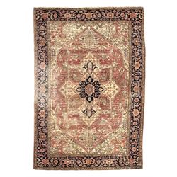 Persian Heriz design rug with red ground, the field featuring a central medallion with floral and geometric motifs, surrounded by ivory spandrels, the main border showcasing a series of floral patterns on a dark blue ground