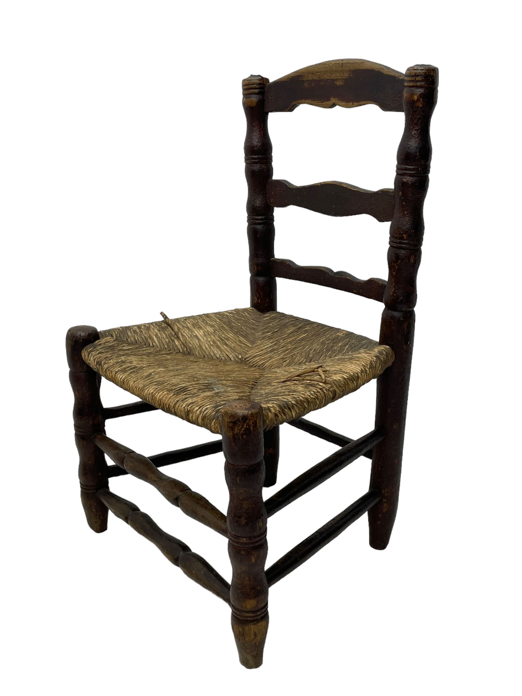 19th century painted elm primitive fire side chair, ladder back over rush seat, on turned supports united by turned stretchers 