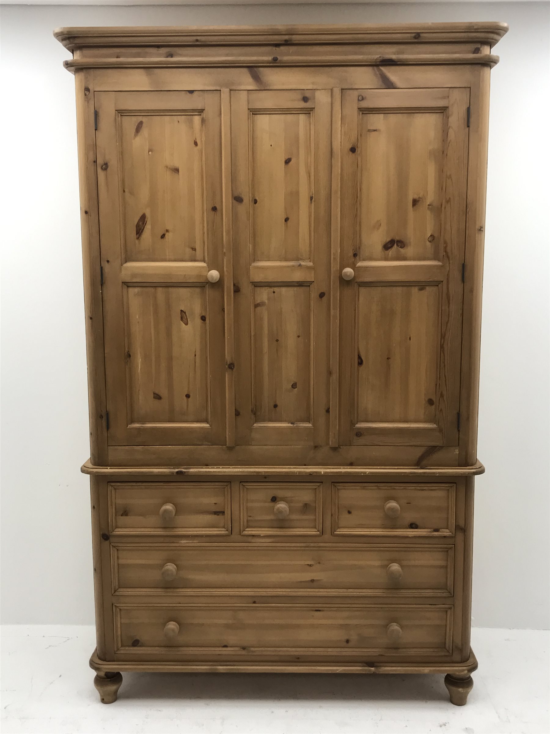 Waxed pine wardrobe enclosed by two panelled doors on chest fitted with three small and two long drawers, turned feet, W125cm, H202cm, D57cm