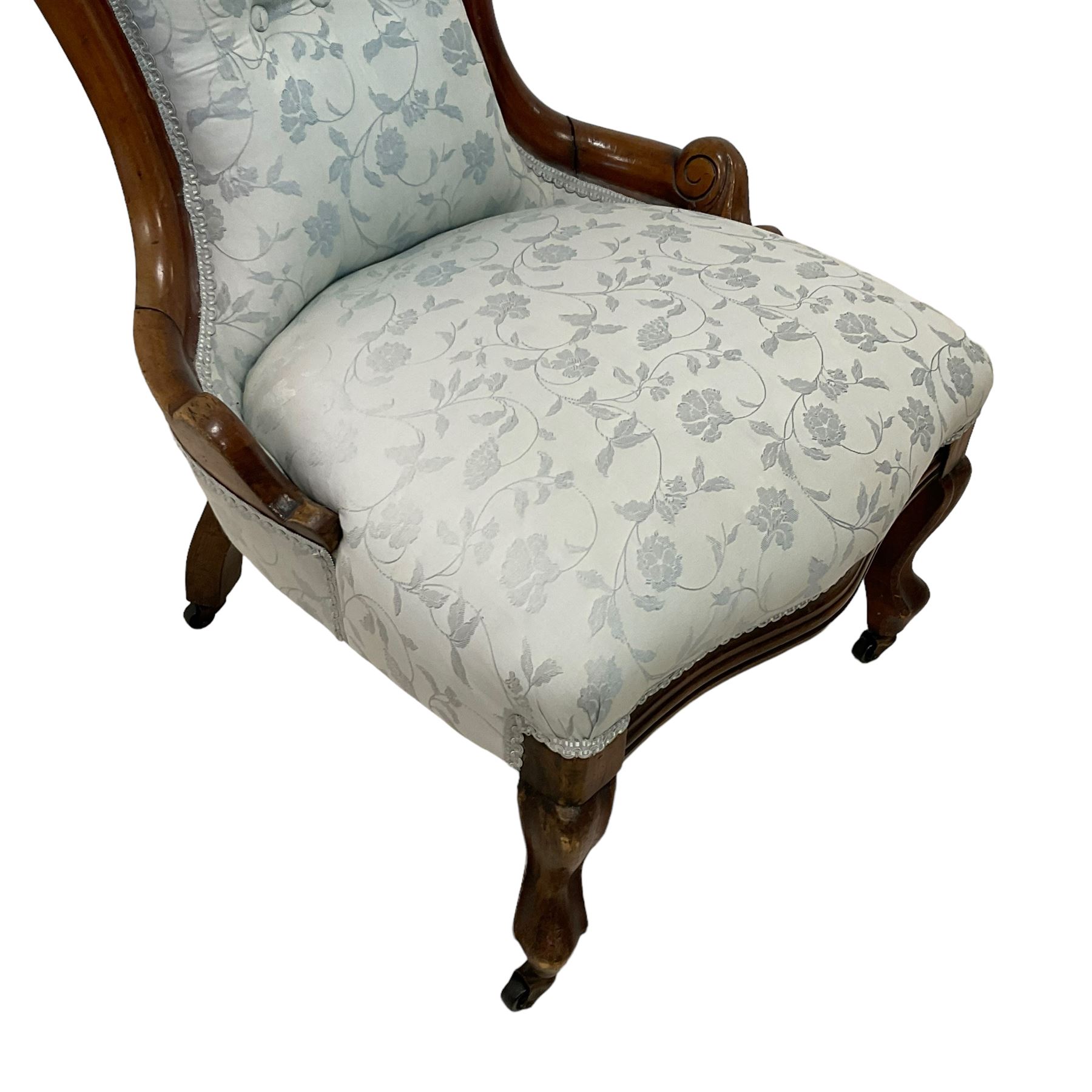 Victorian walnut nursing chair, the curved cresting rail carved with central cartouche and scroll leaves, upholstered in pale blue fabric decorated with trailing floral design, on cabriole front feet 