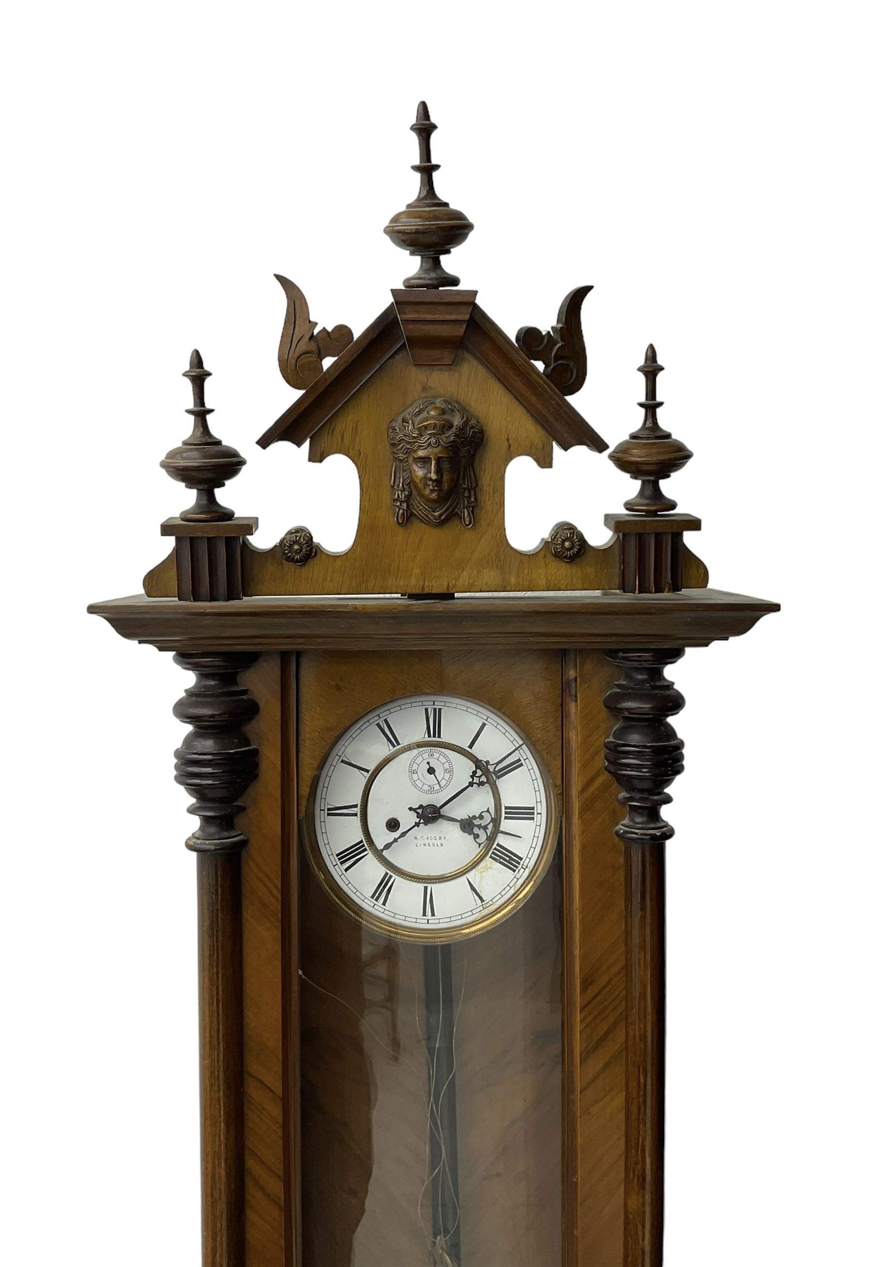 German - late 19th century walnut and ebony twin train weight driven Vienna regulator, with a fully glazed door, shaped pediment with carved pilasters and turned finials, two part enamel dial with Roman numerals, seconds dial and gothic steel hands, brass faced pendulum bob with an ebonised wooden rod and two brass cased weights, movement with a dead-beat escapement and rack striking on a coiled gong.