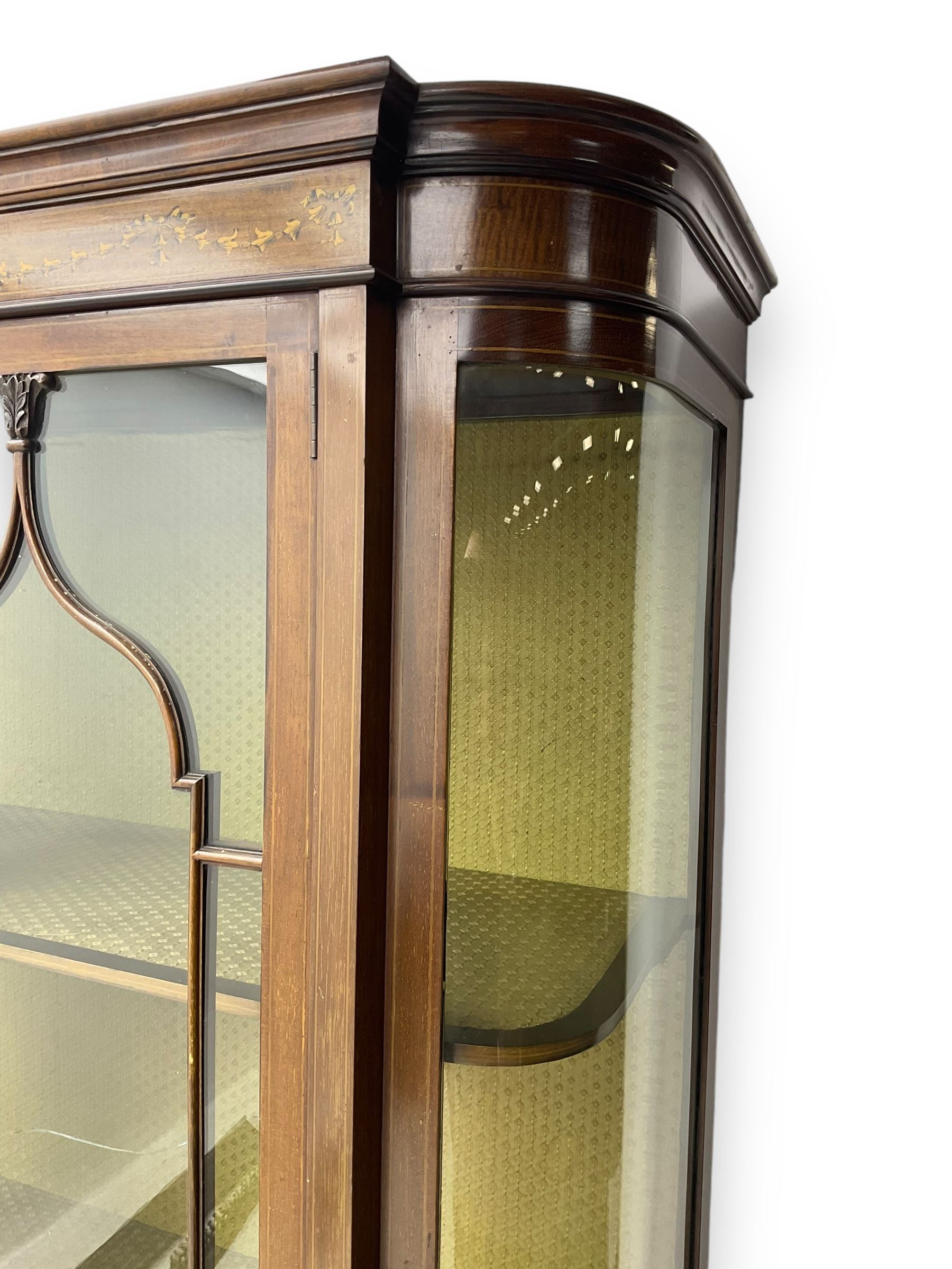 Edwardian inlaid mahogany display cabinet, projecting moulded cornice over two glazed doors, flanked by curved glazed sides and central arched panel with floral medallion, raised on square tapering supports with spade feet united by undertier