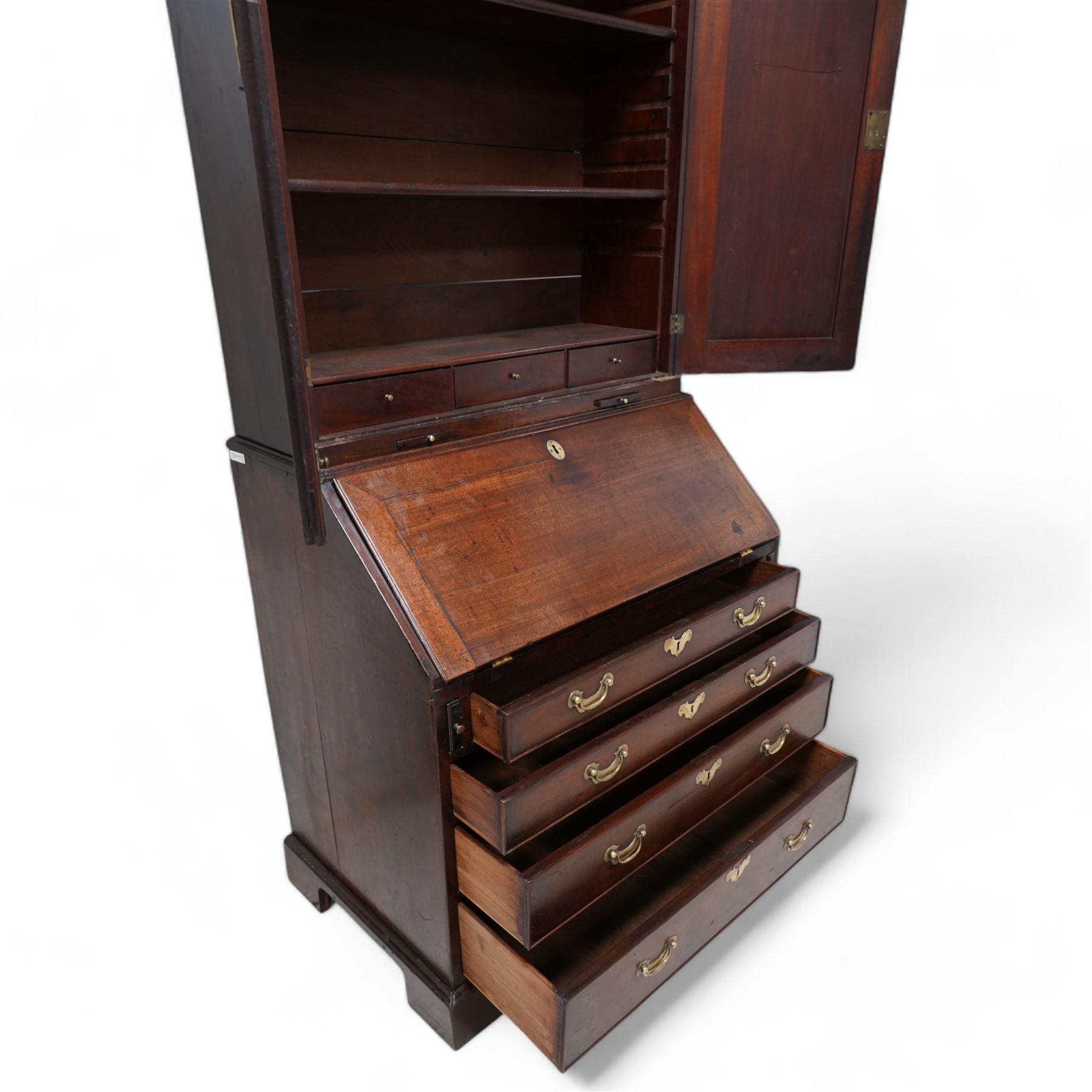 18th century mahogany bureau bookcase, cavetto moulded cornice over two panelled doors and candle slides, the interior fitted with adjustable shelves and small drawers, moulded fall front enclosing pigeonholes, small drawers and cupboard, four long graduating cock-beaded drawers below with shaped brass handles, on bracket feet 