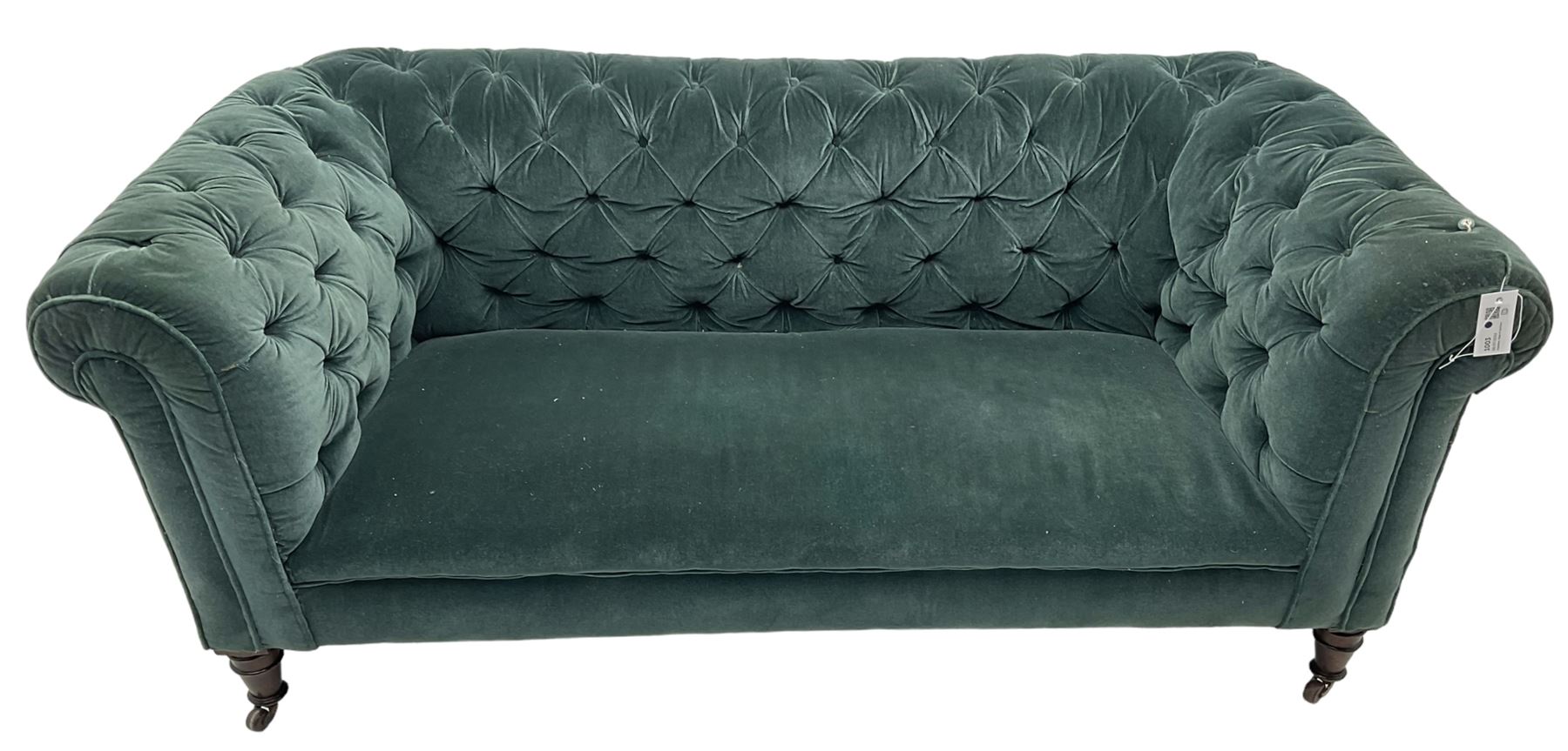 Victorian hardwood-framed Chesterfield sofa, traditional shape with low back and rolled arms, upholstered in teal buttoned fabric, on turned front feet with brass and ceramic castors 