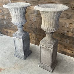 Pair of large Georgian design cast stone garden urns, egg and dart border, tapering column on square base, raised on square column