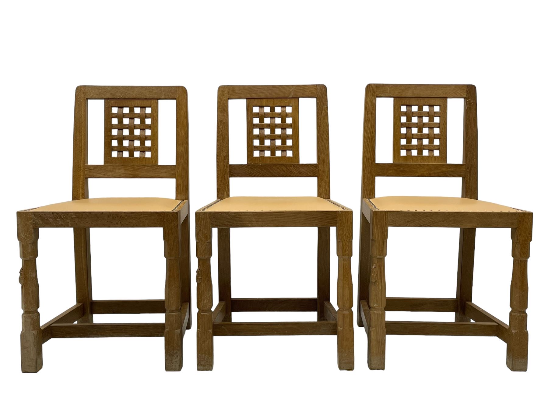 Mouseman - set of six oak dining chairs, pierced and carved lattice panel back over tan leather seat with studded band, on octagonal front supports united by plain H stretchers, carved with mouse signature, by the workshop of Robert Thompson, Kilburn 