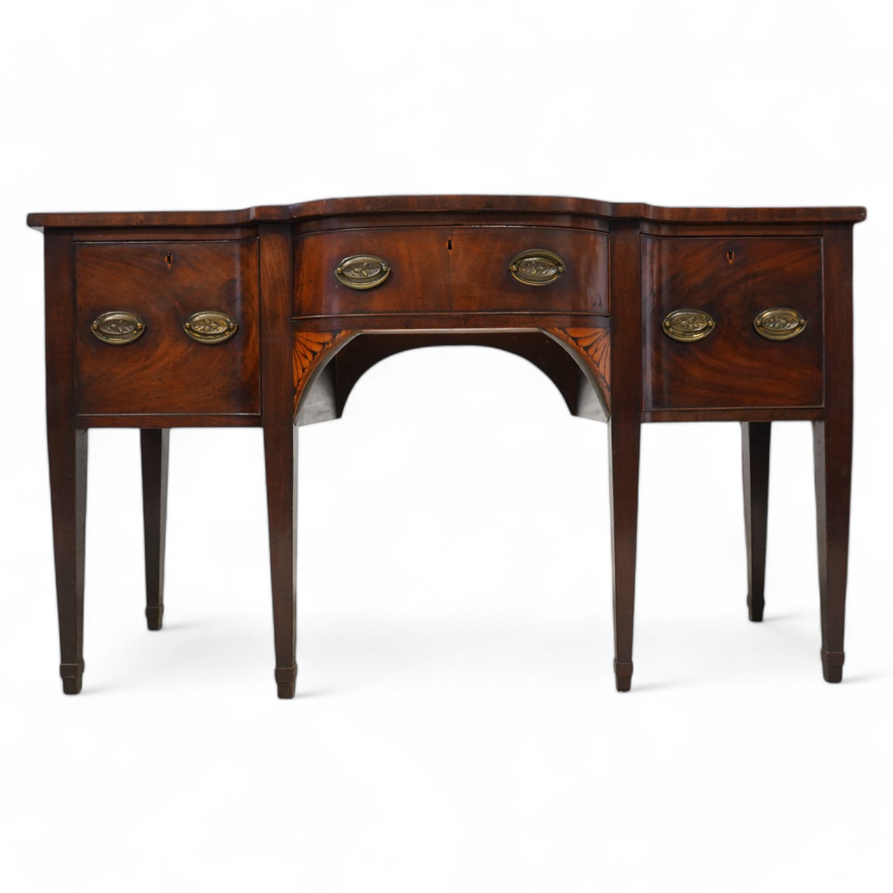 George III mahogany break bow-front sideboard, fitted with three drawers, the corner brackets inlaid with quarter shell motifs, pressed brass oval handle plates decorated with oak leaves and acorns, on square tapering supports