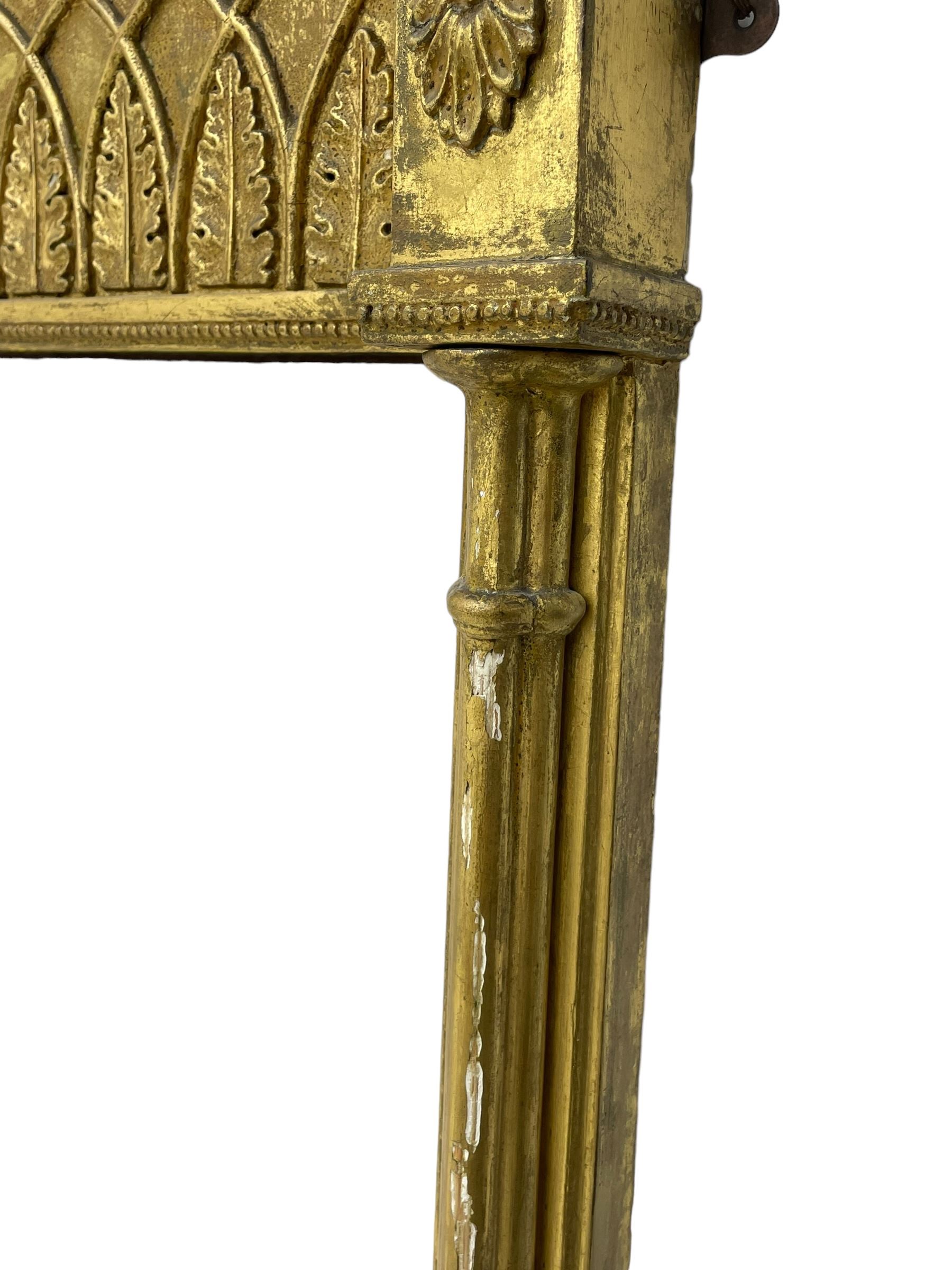 Regency giltwood and gesso pier mirror, projecting cavetto cornice with ball mounts, the frieze decorated with pointed arcade and foliate motifs, plain mirror plate enclosed by cluster column pilasters 