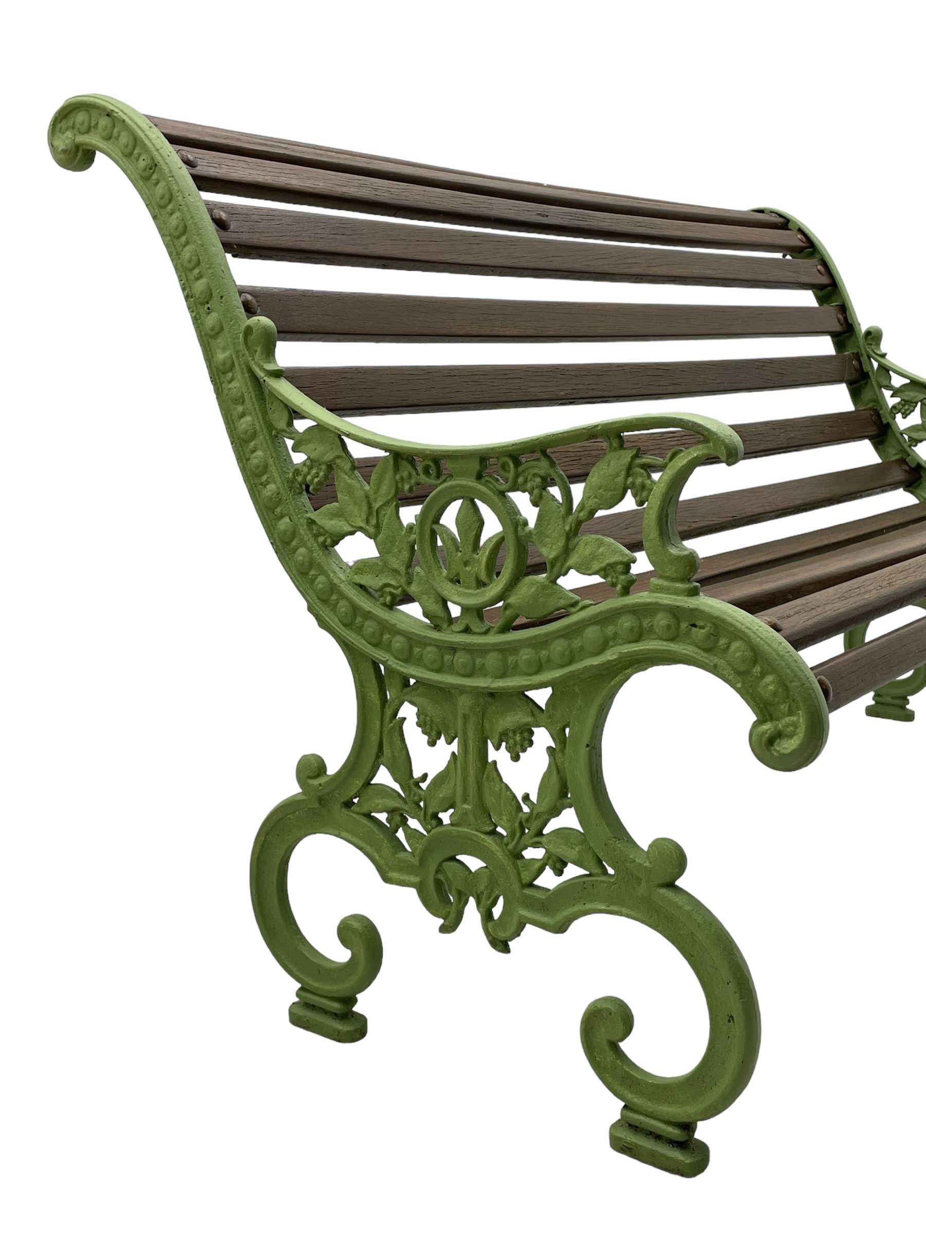 20th century cast iron and wood slatted 'Lilly of the Valley' garden bench, cast iron bench ends of scrolled form decorated with trailing foliage and flower heads, on scrolled supports 