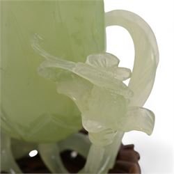 Chinese green jade magnolia form vase, supported on a leafy stem, with flowers and butterflies, on a pierced and carved hardwood stand, H15cm x W14cm