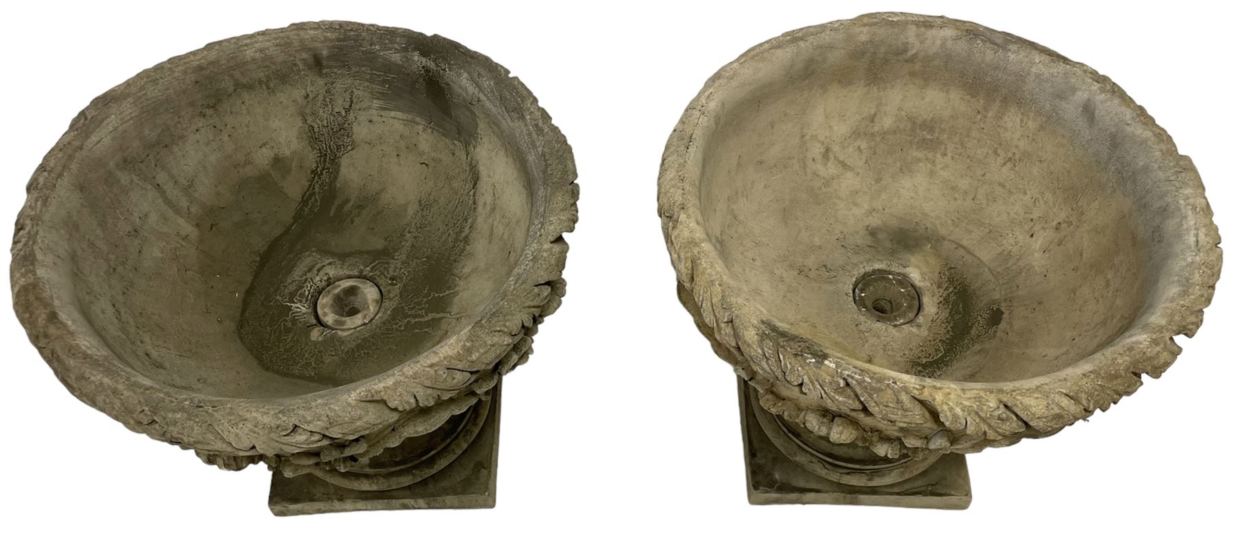 Pair of composite stone garden urn planters, acanthus leaf garland rim over foliate decorated body, stepped foot on square base