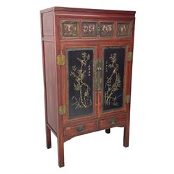 Late 19th century Chinese Qing dynasty red and black lacquered wood cabinet, Fujianese province, upper cupboard enclosed by two doors with relief carved and gilt panels depicting figures behind glass, the large cupboard enclosed by two panelled doors carved with trailing foliate branches and birds, inscribed with Chinese characters, to the left ‘Prolong life’ and to the right ‘Wealth and good fortune’, fitted with two drawers, square supports with carved brackets 