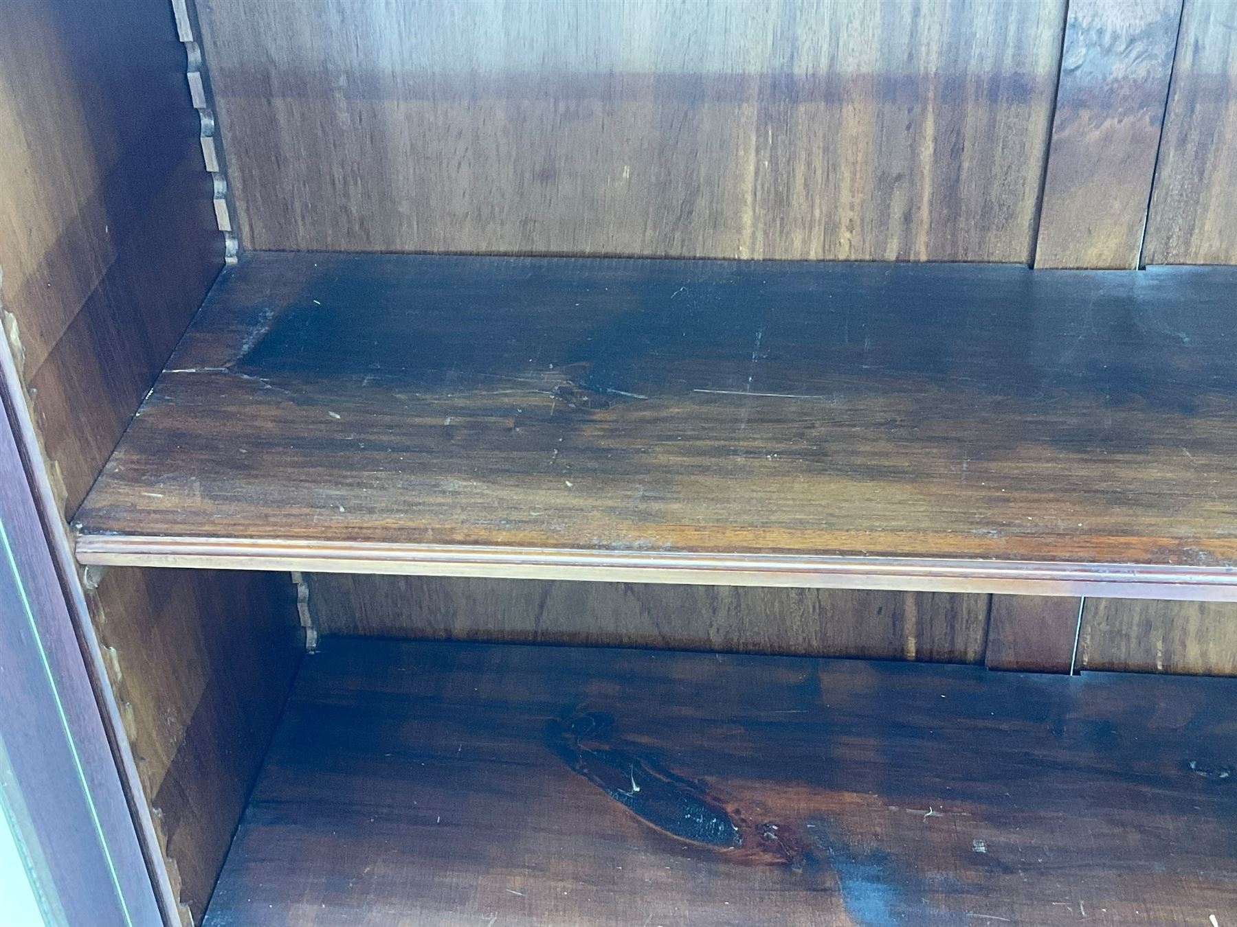 Early 20th century mahogany bookcase, projecting dentil cornice over blind fretwork frieze, enclosed by two astragal glazed doors, on shaped bracket feet 