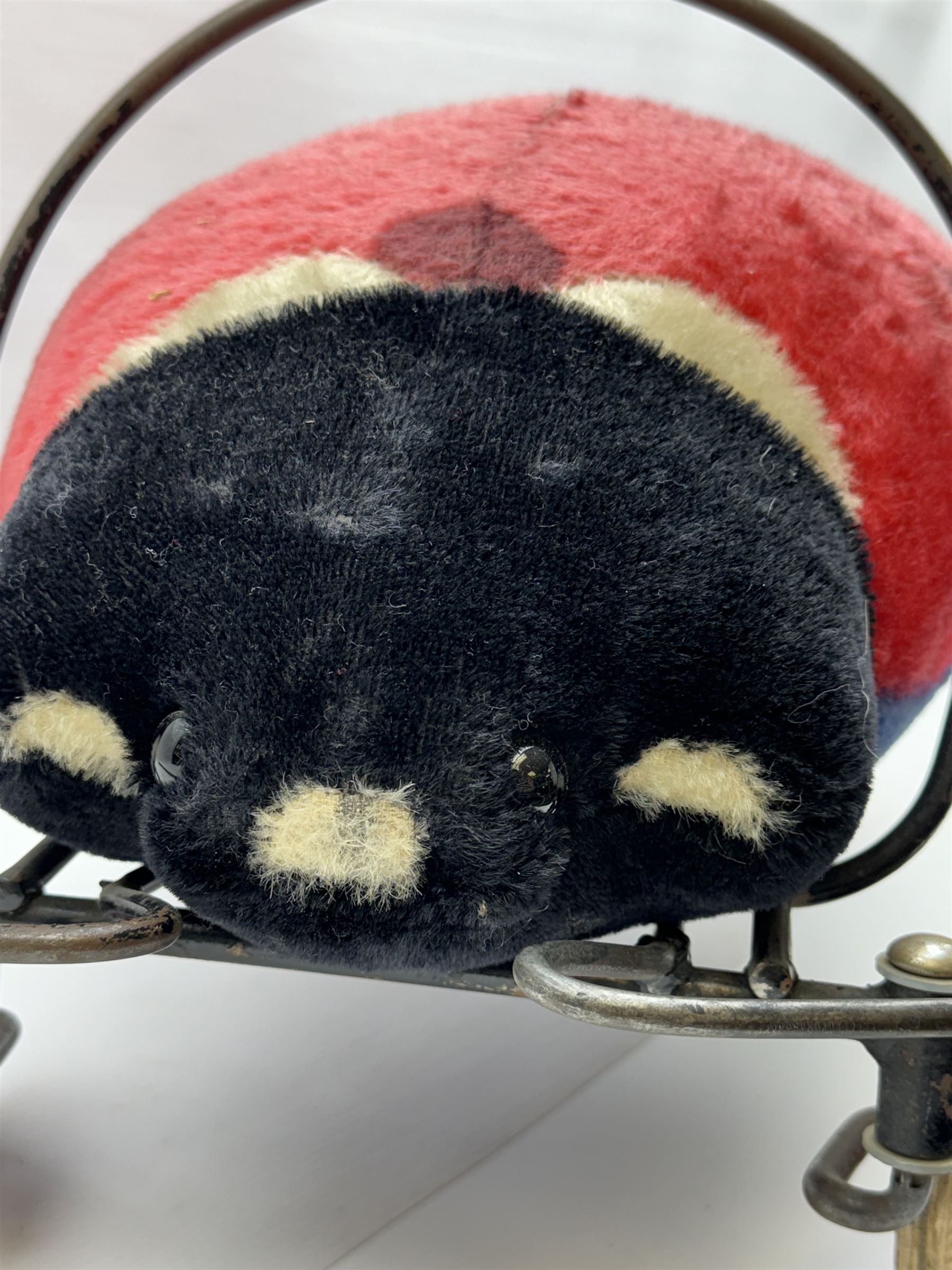 Steiff child's ride on ladybird, circa 1950s, the mohair body with red and black spotted seat, black and white face and blue underbelly, upon a metal frame with rubber and metal wheels, H30cm, W52cm