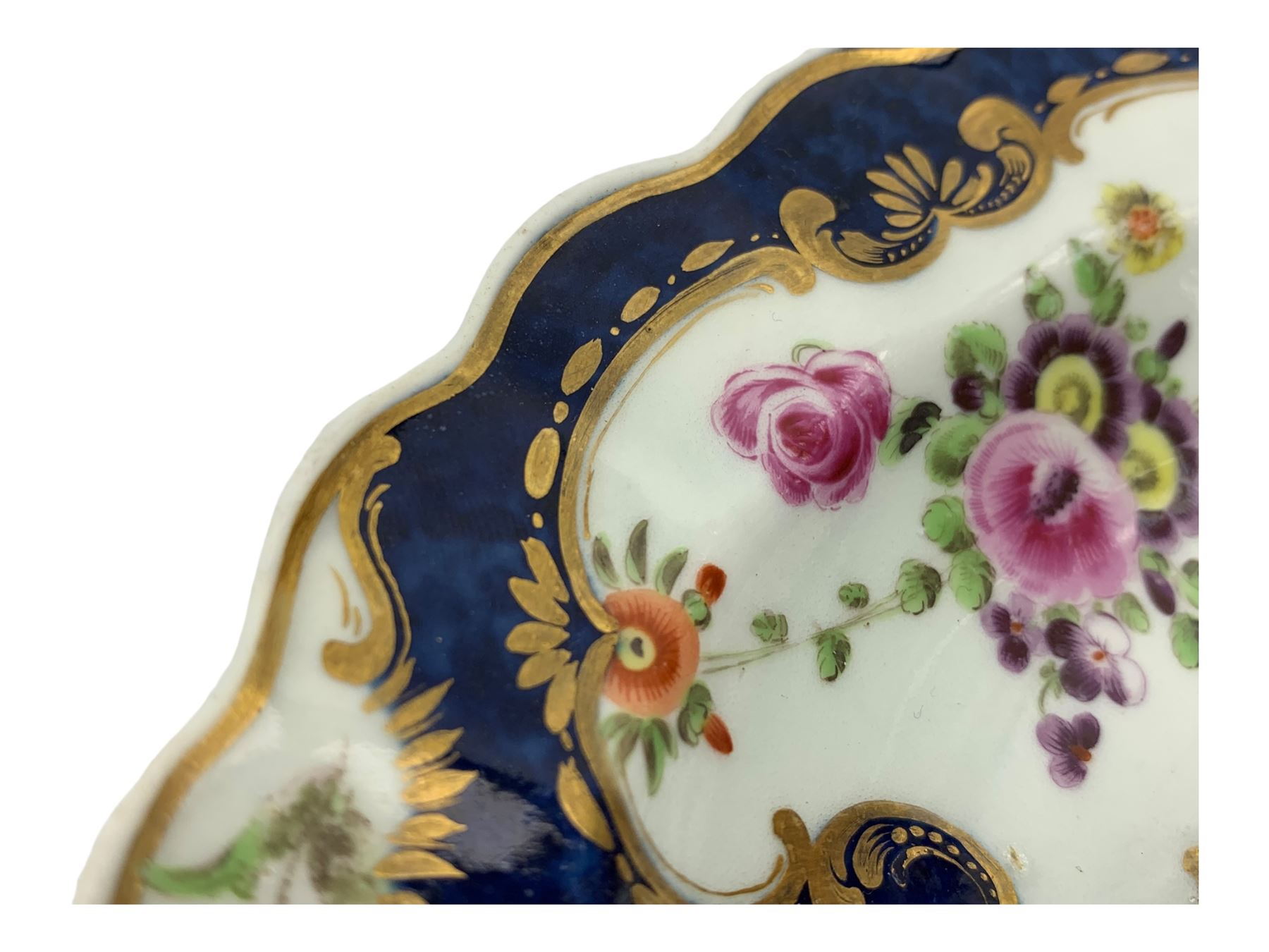 18th century Worcester tea caddy, of oval form and painted in the Kakiemon palette with reserves of flowers against a blue scale ground, H14cm together with a similar Worcester circular dish, painted with floral sprays, within a scalloped edge, blue crescent mark beneath, D19cm (2)