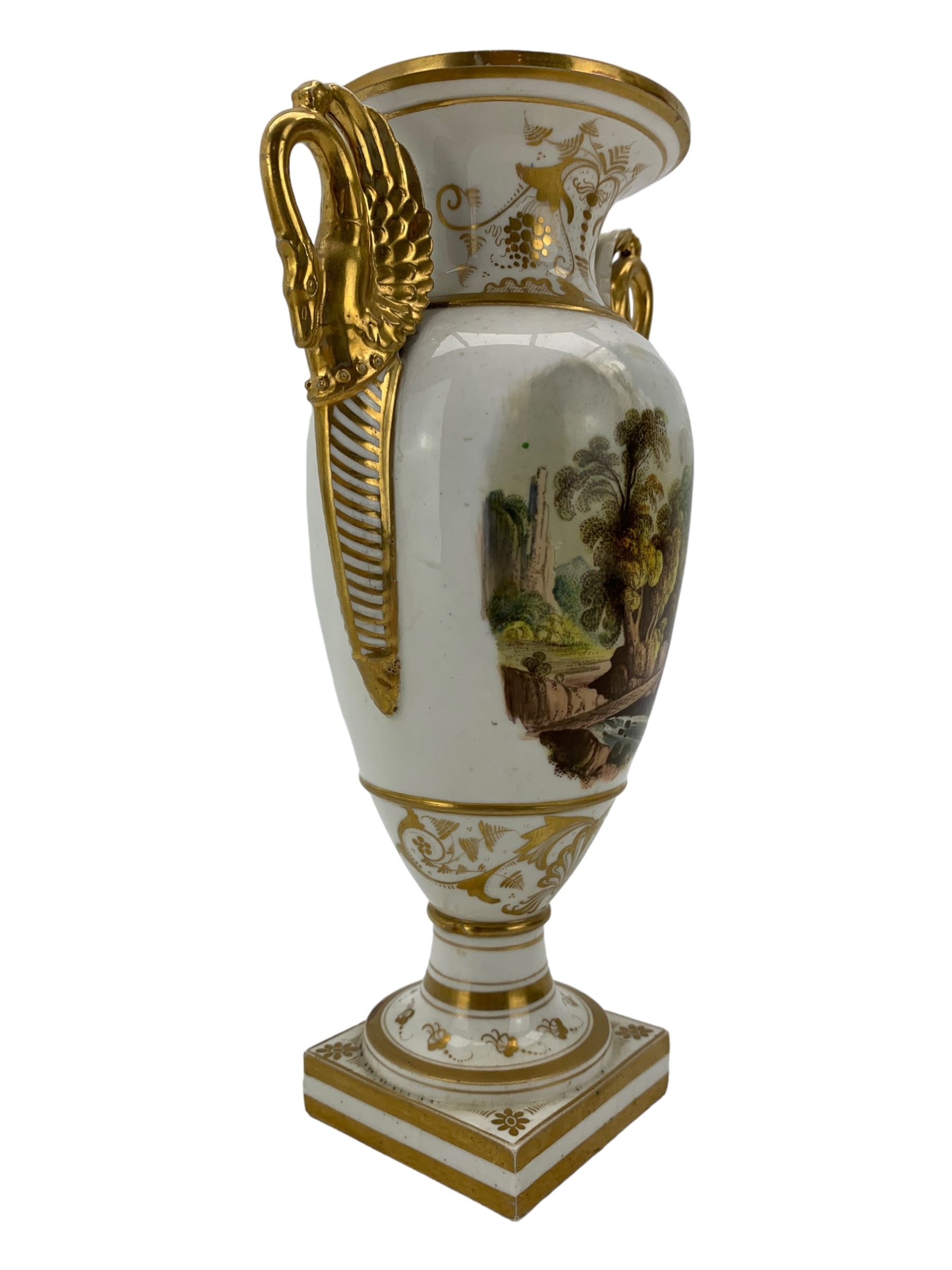 Early 19th century Derby vase, of campana urn form, decorated to one side with a hand painted reserve of a basket of flowers, within a scroll gilt border and twin serpent form handles, H20.5cm together with a Bloor Derby vase, hand painted with figures in a wooded landscape, with twin gilt swan form handles, upon a square pedestal foot, H25cm (2)