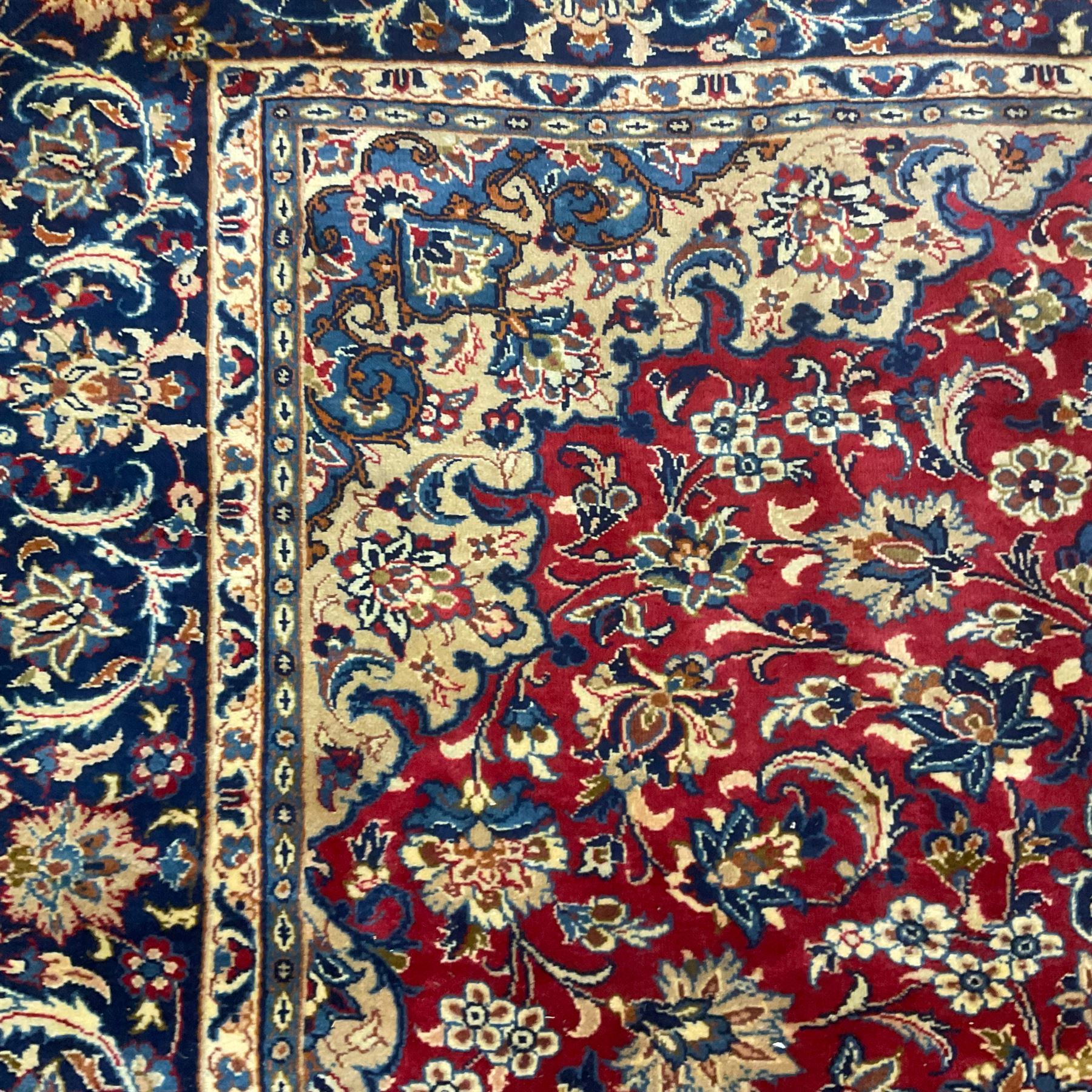 Persian Kashan red ground carpet, the field decorated with central medallion surrounded by trailing branches and stylised plant motifs, blue ground border with scrolling floral design 