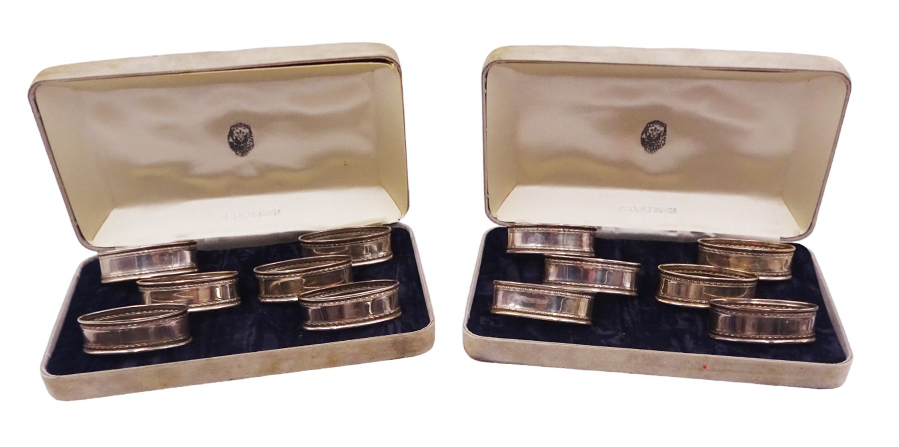 Two sets of six modern silver napkin rings, each of oval form, with Greek key decoration, hallmarked Ari D Norman, London 1986, both in fitted cases