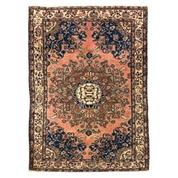 Persian Hamadan ground rug, central medallion design with a salmon pink field, accentuated by navy blue spandrels, surrounded by a stylised floral border in cream and blue tones