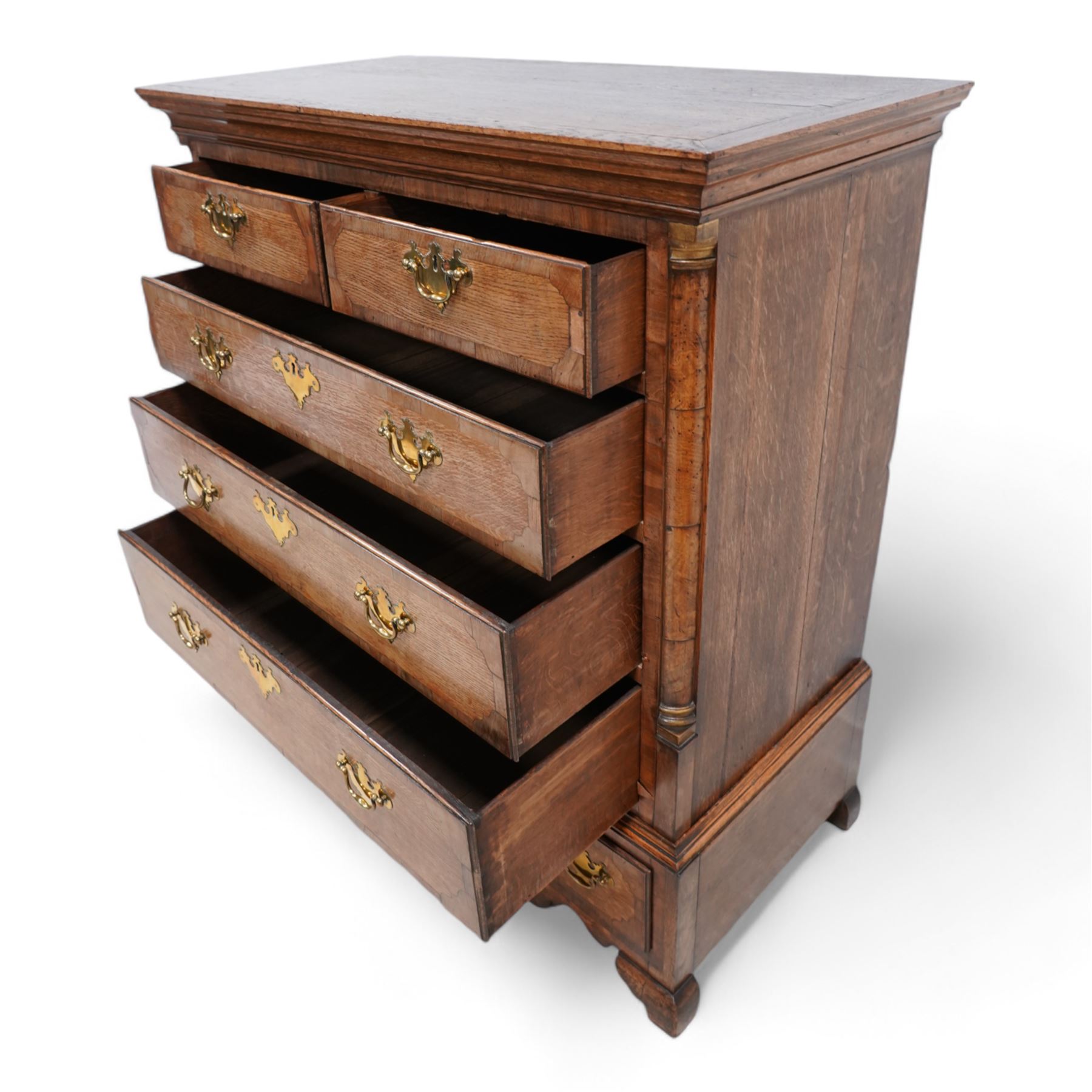 George III oak and mahogany banded chest on stand, moulded cornice over two short and three long drawers, shaped brass handle plates and swan neck handles, enclosed by canted corners with turned quarter columns, the stand fitted with three drawers, on bracket feet