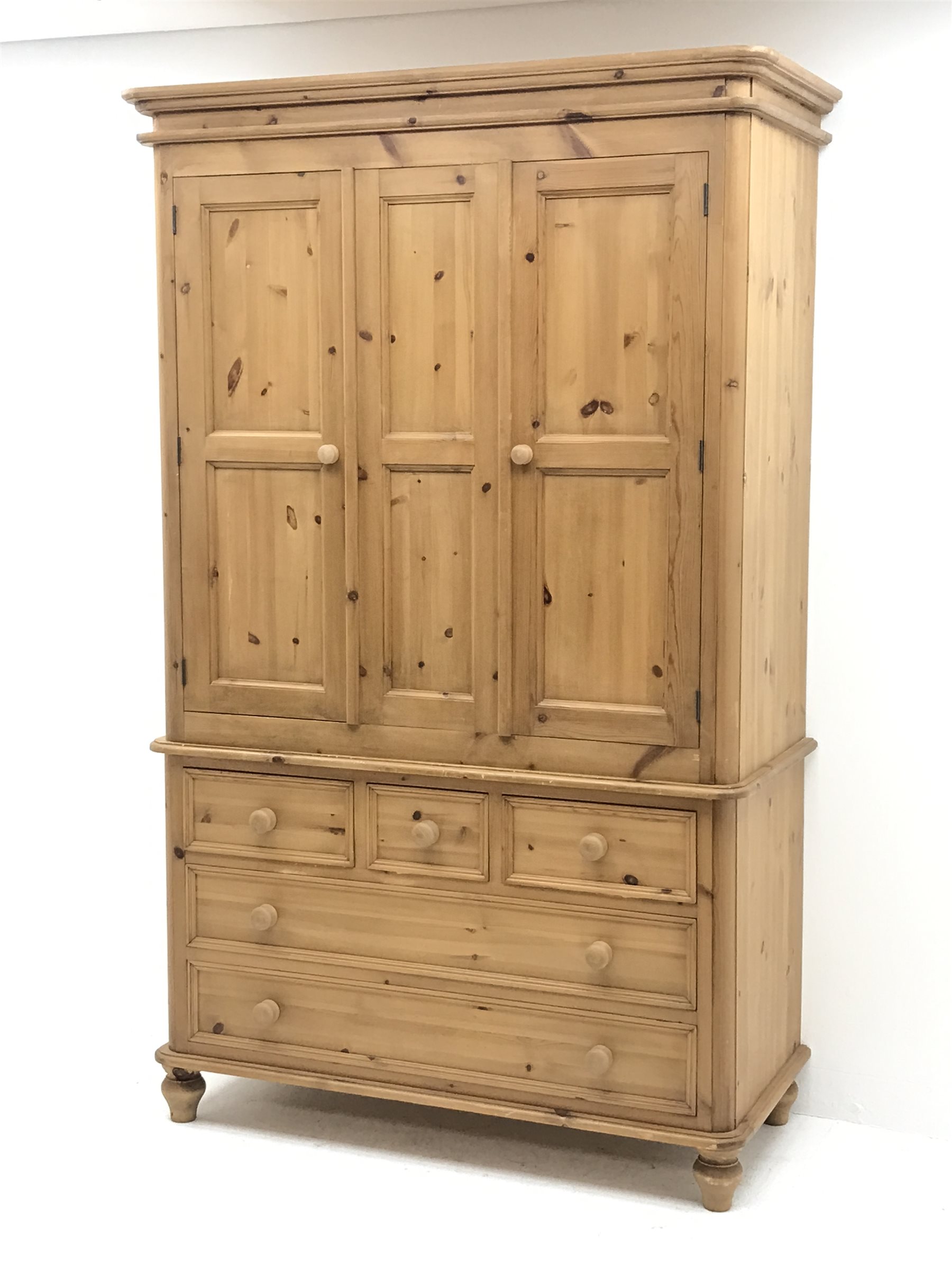 Waxed pine wardrobe enclosed by two panelled doors on chest fitted with three small and two long drawers, turned feet, W125cm, H202cm, D57cm