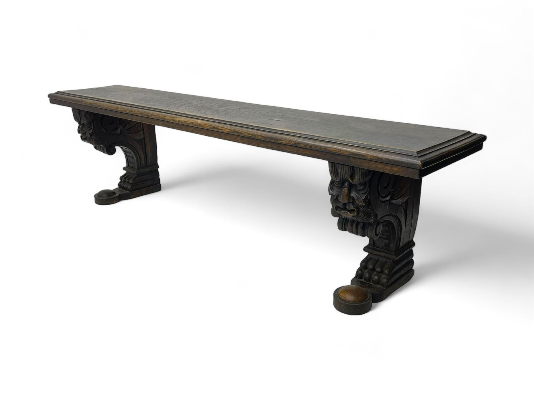 Victorian oak bench, moulded rectangular top, on mask and scroll carved corbel supports with paw feet, rectangular platforms with rounded terminals and applied roundel 