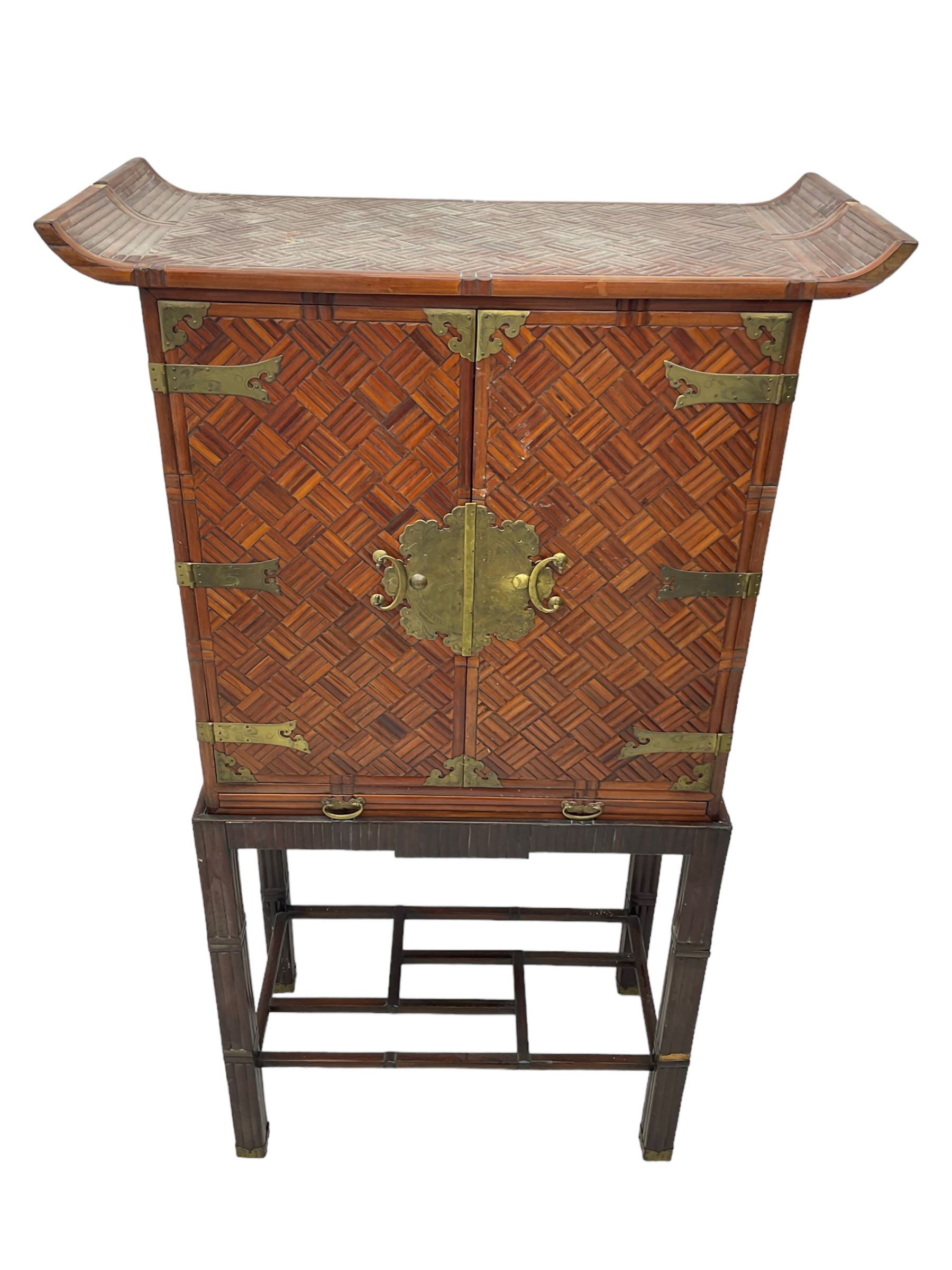 Chinese design bamboo and wood altar cabinet on stand, parquetry lattice-work bamboo, two doors with engraved metal fixtures enclosing drawers and shelf, fitted with slide, the stand pm square supports joined by a series of geometric stretchers