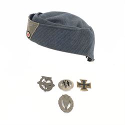 Four reproduction WWII German badges, including Iron Cross, German Proficiency SS runes badge, etc together with a reproduction German cap 