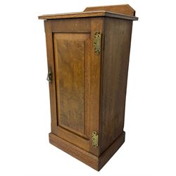 Edwardian oak bedside cabinet, raised back over moulded top, enclosed by panelled door, the interior fitted with shelves, on chamfered plinth base 